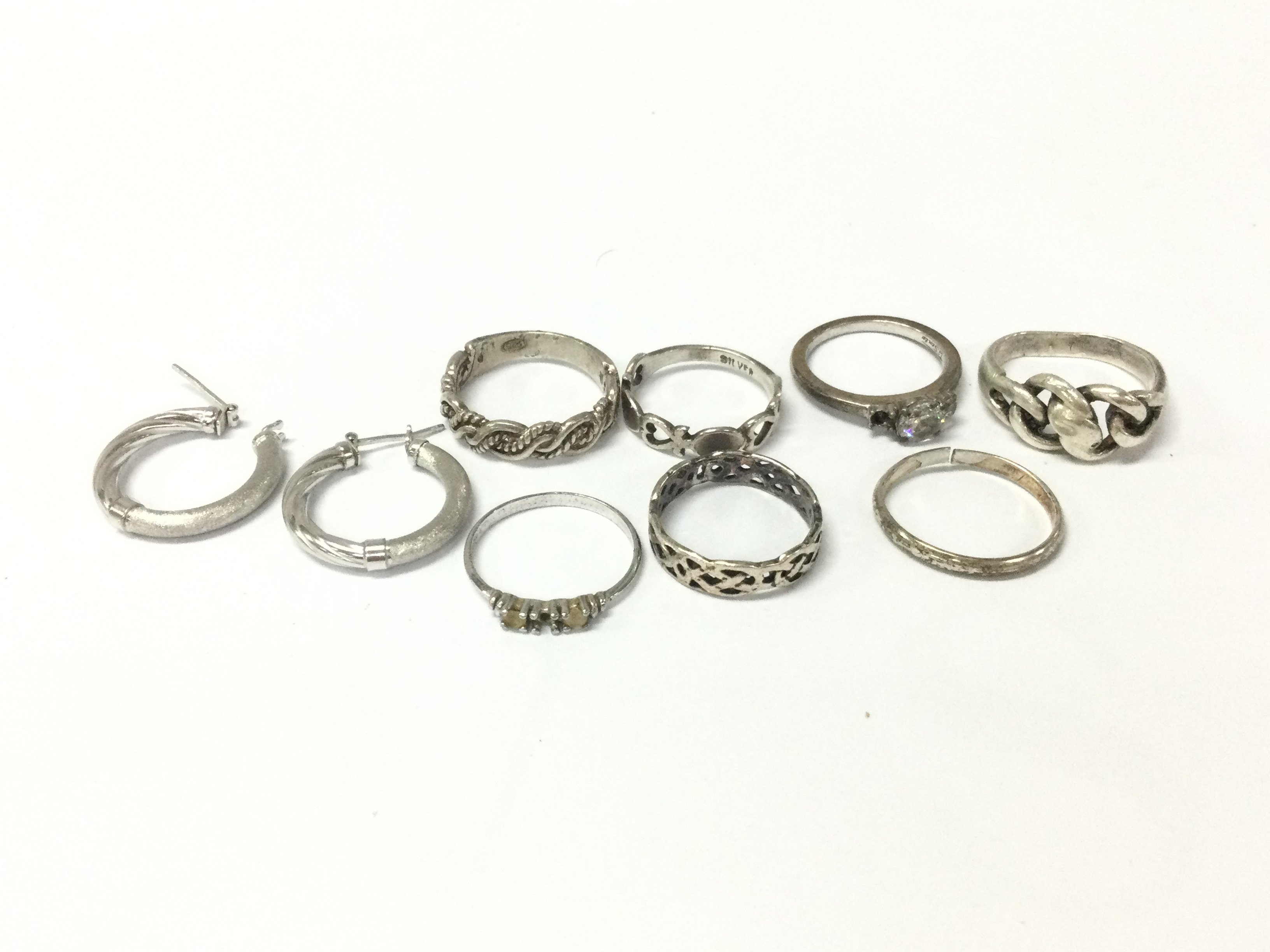 A collection of silver rings and a pair of silver earrings. Postage A