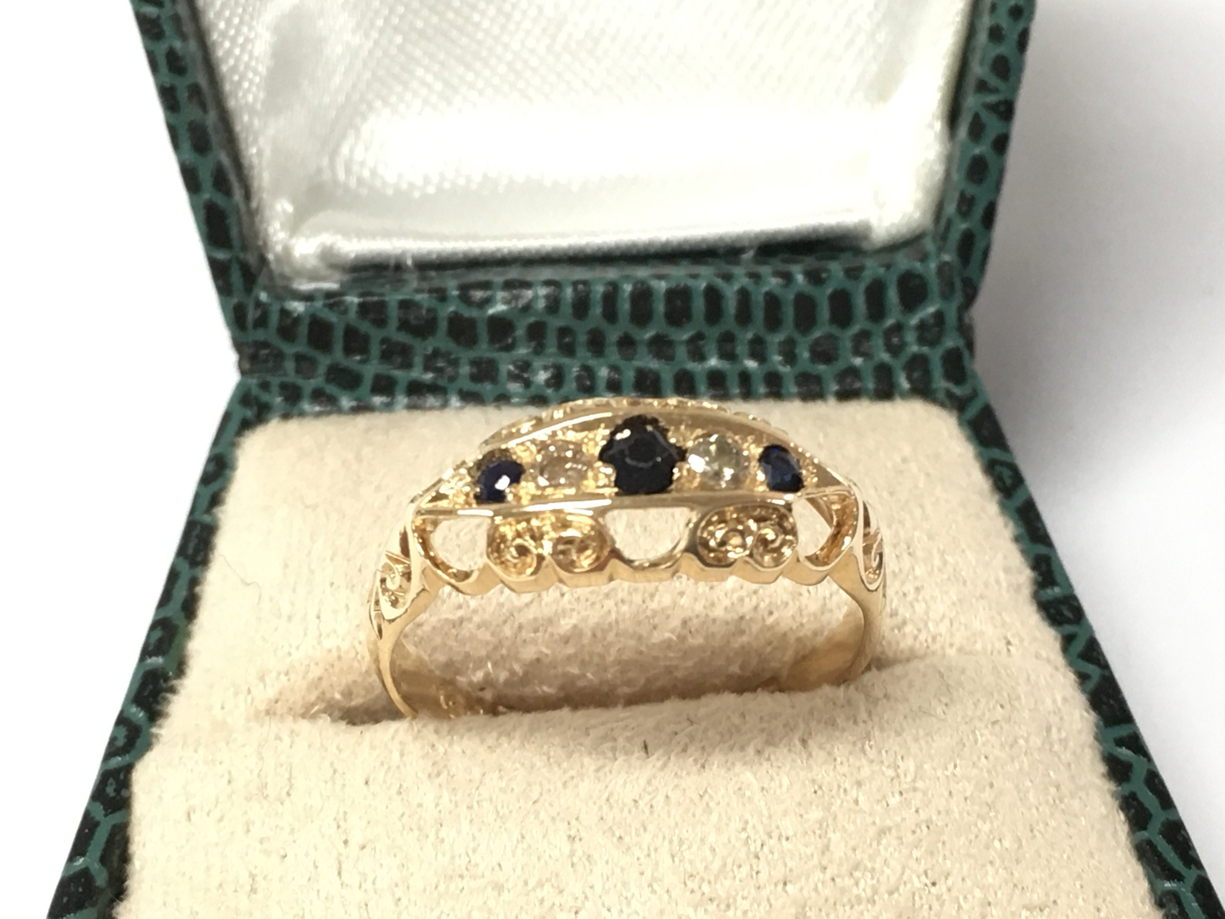 An 18ct yellow gold sapphire and diamond ring with carved detailing. Circa 1915. Sapphire 0.10ct and diamonds 0.04ct Approx. Size L