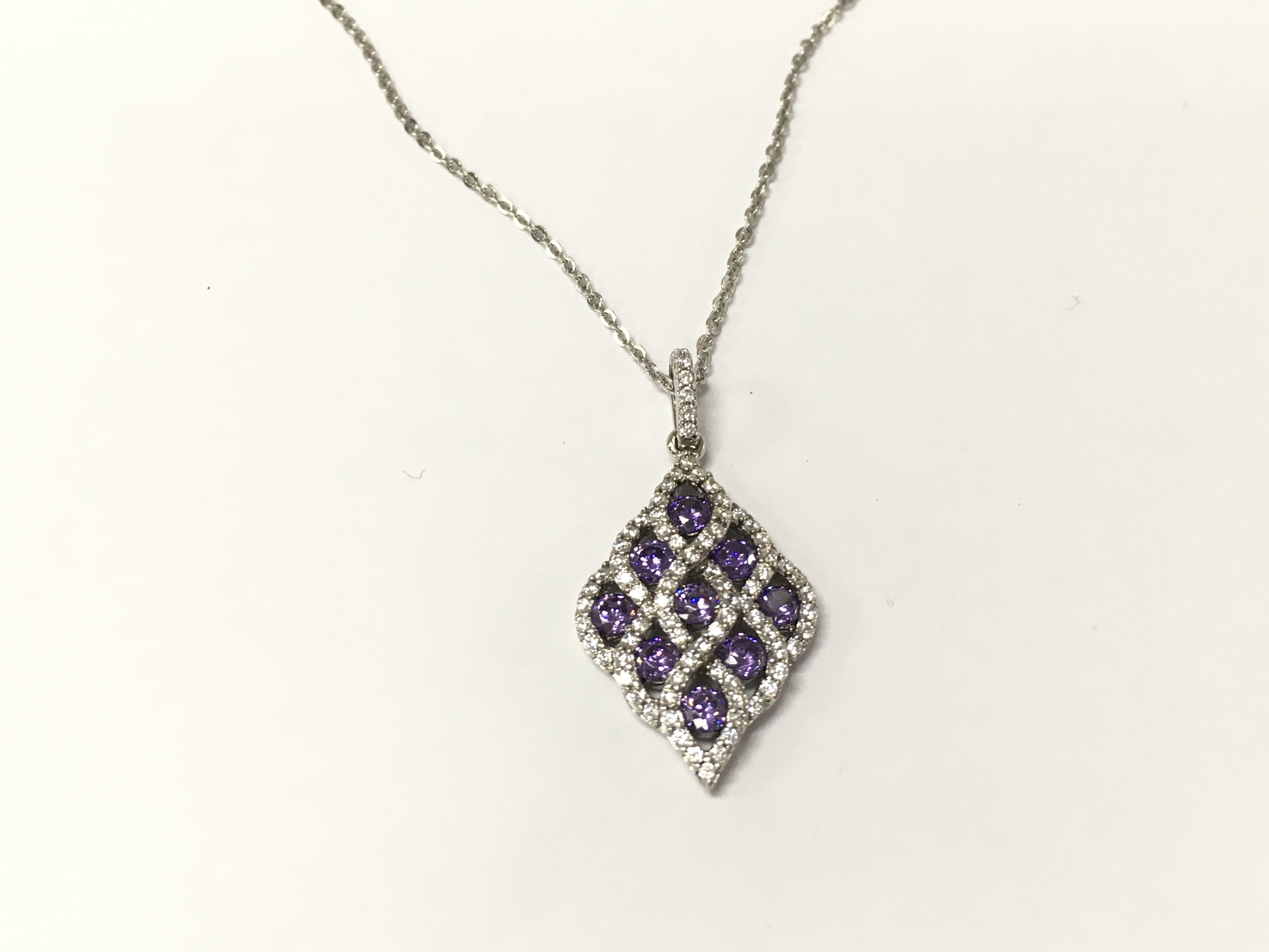 A silver pendant set with purple and white cubic zirconia on a silver chain. Postage A