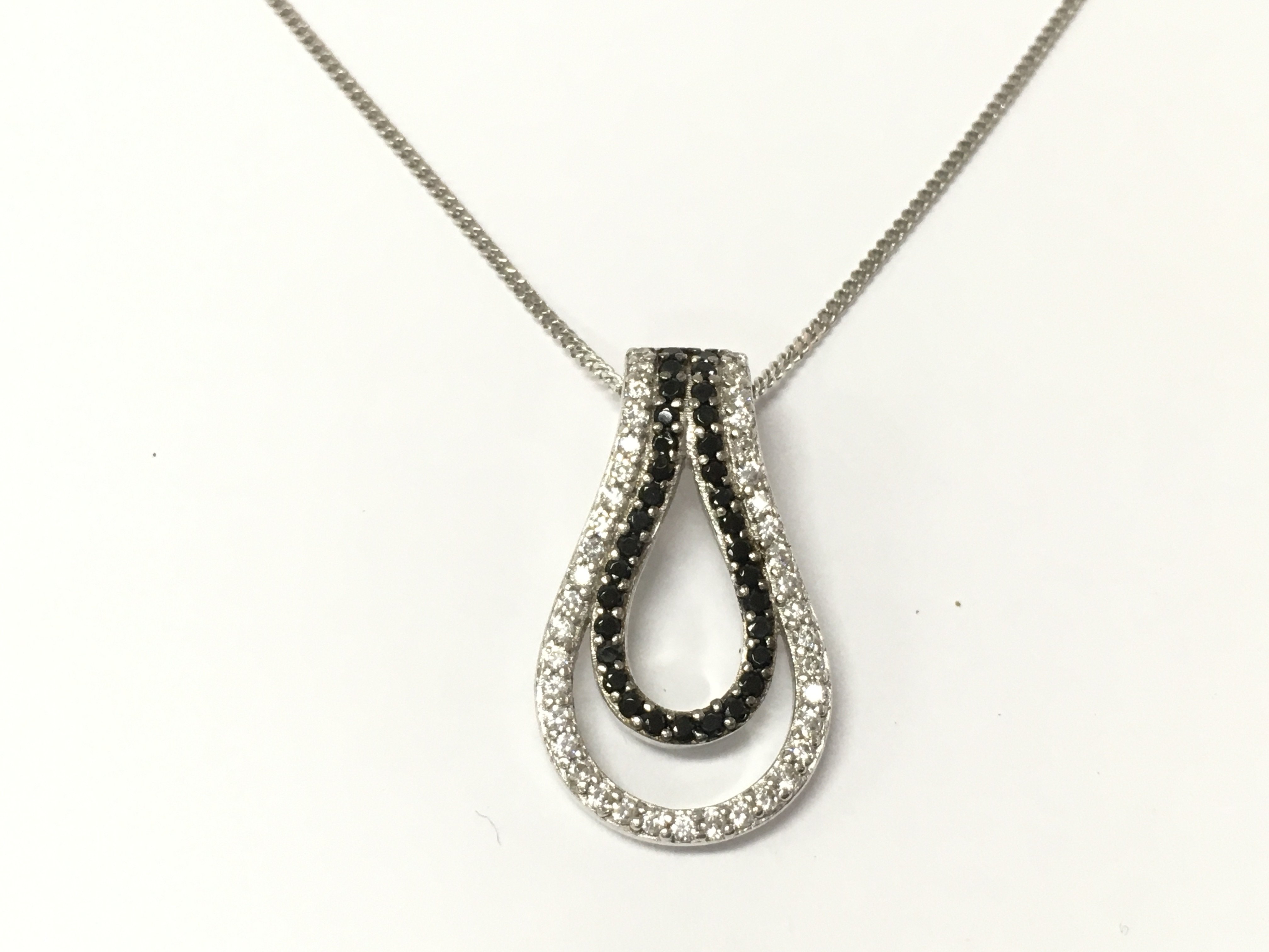 A double pair shaped silver pendant set with black and white cubic zirconia on a silver chain. Postage A