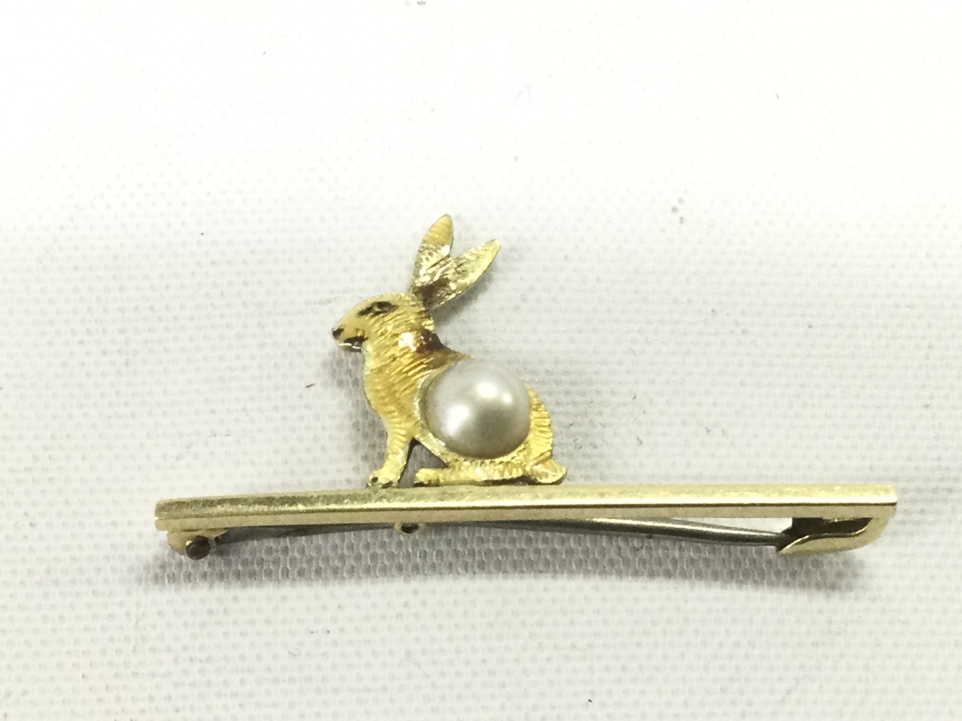 An 18ct gold beooch in the form of a rabbit and set with a pearl, approx 2.2g.