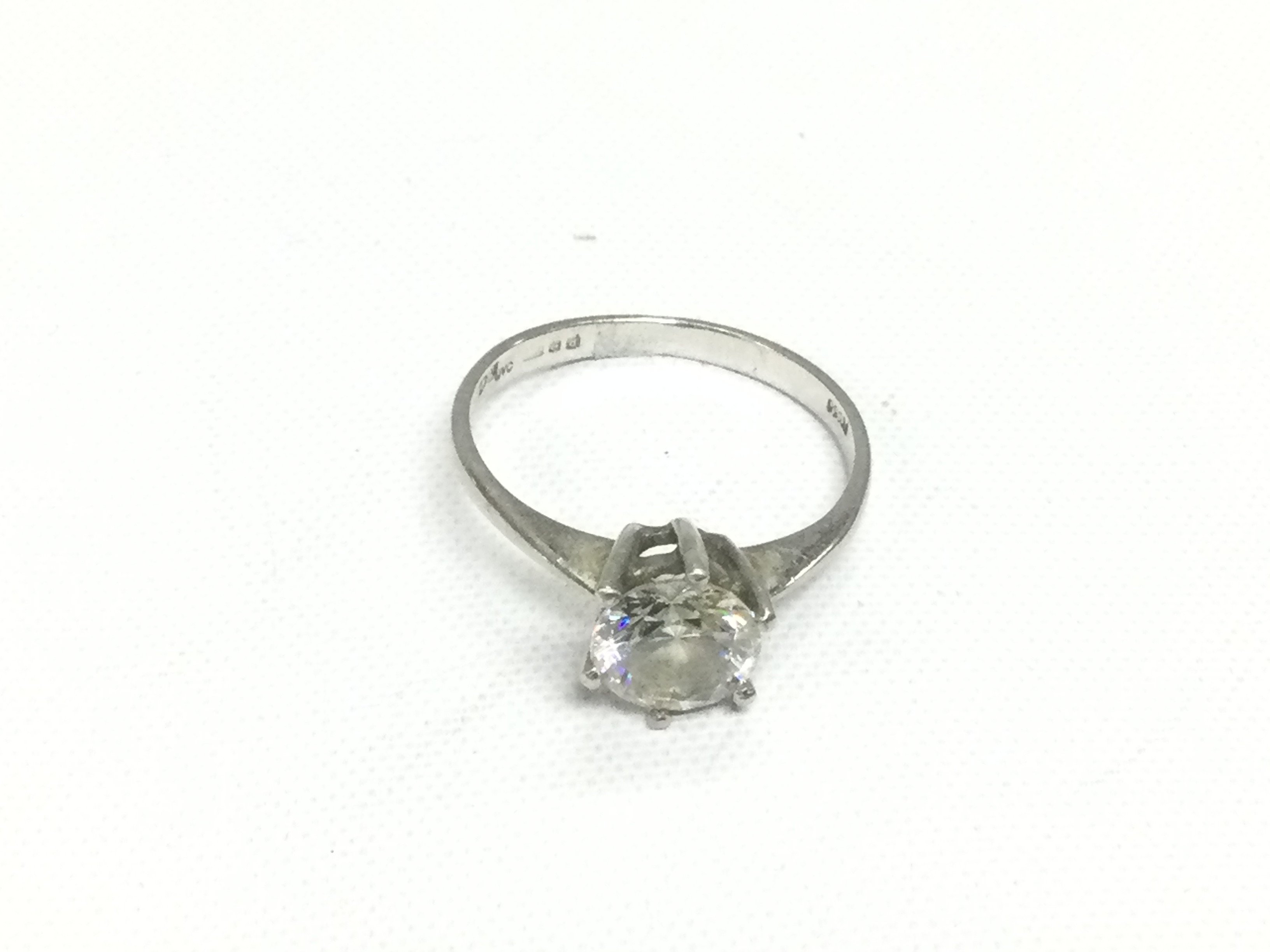 A platinum and moissanite solitaire ring, approx size M. Shipping category A.