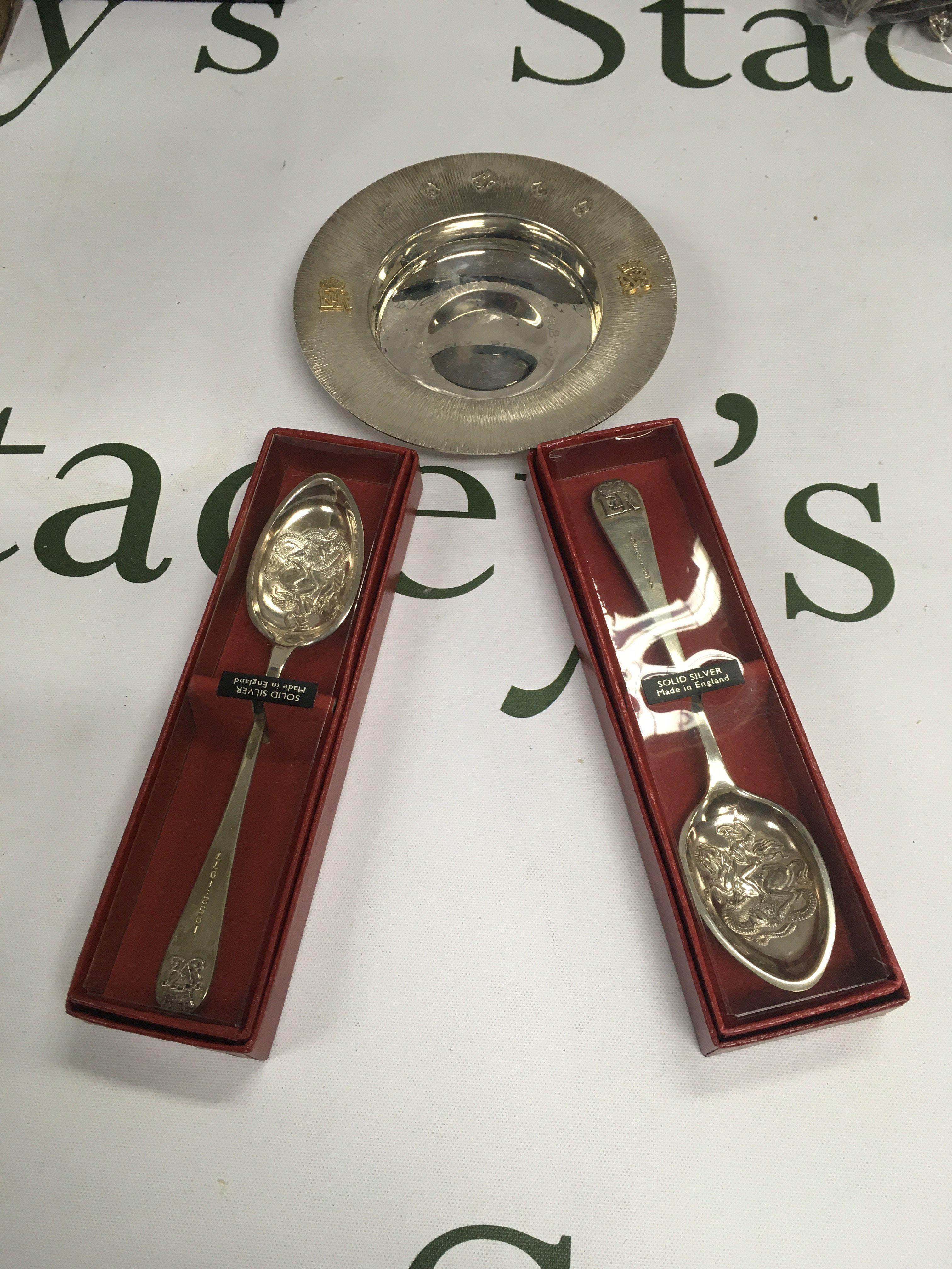 A comemorative tray and two commemorative cased silver spoons.