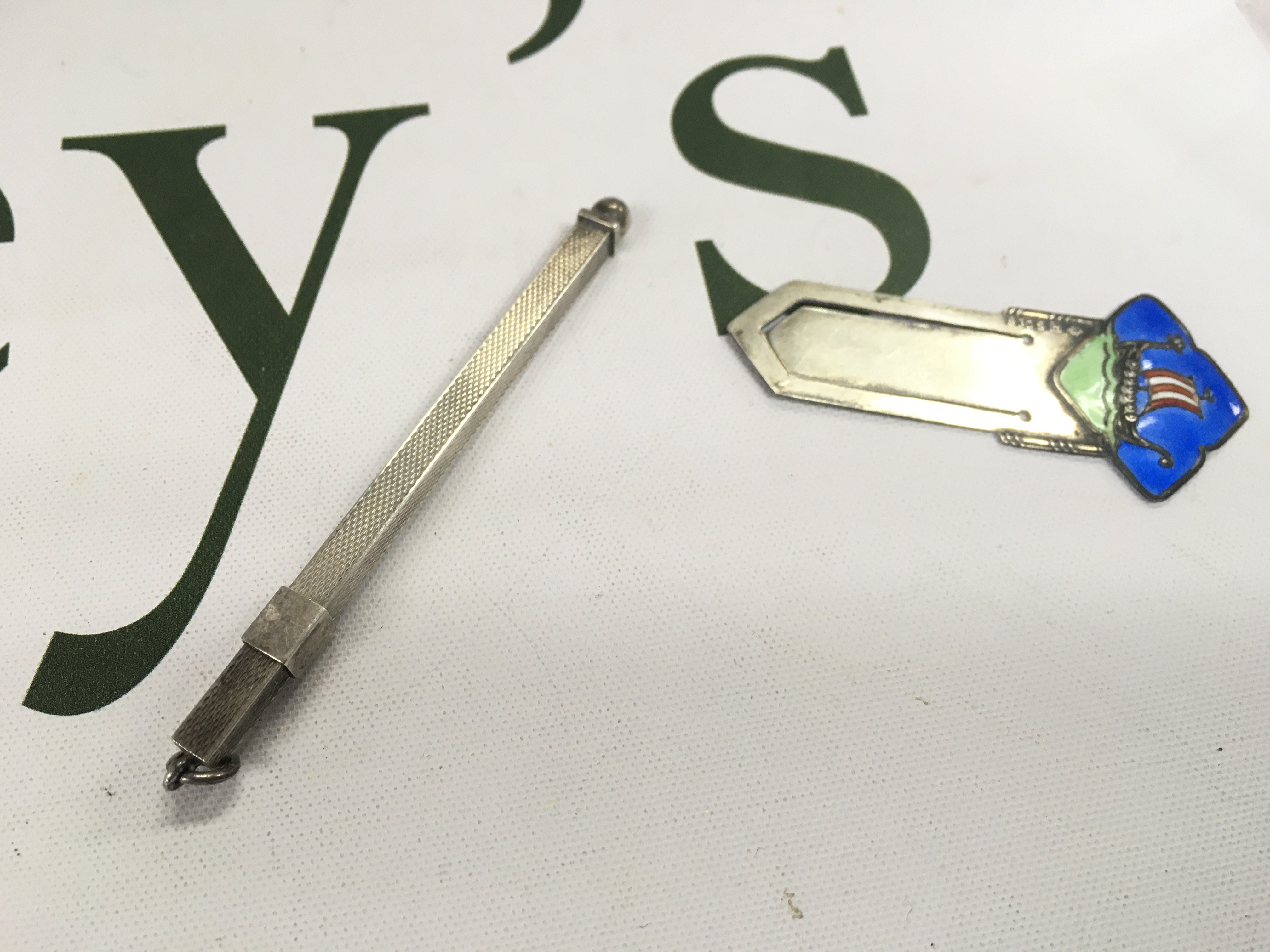 A silver enamel clip with a silver cocktail stirrer.