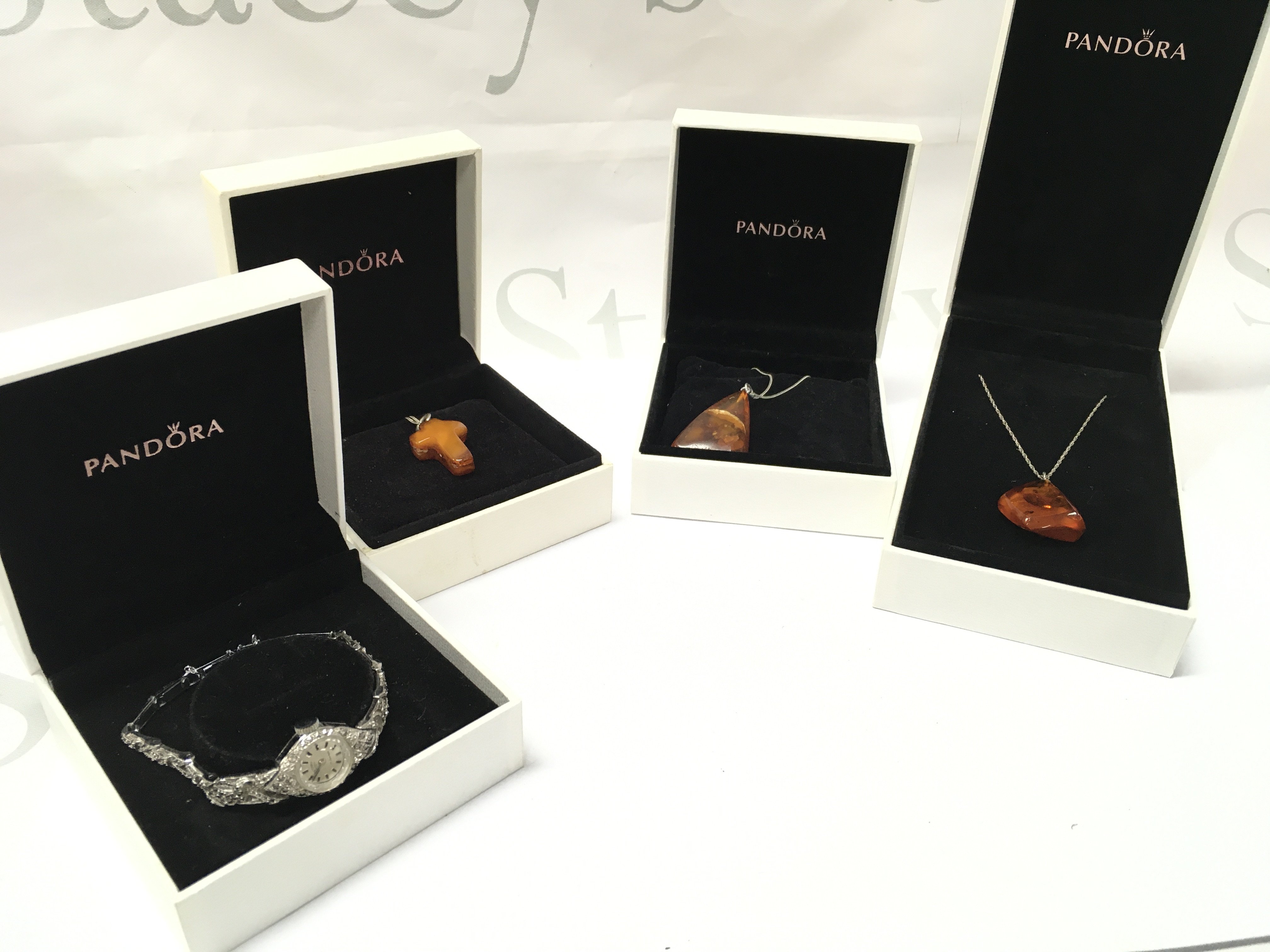 Three ladies amber pendants on silver chains and a ladies rotary watch, marquisette seen working