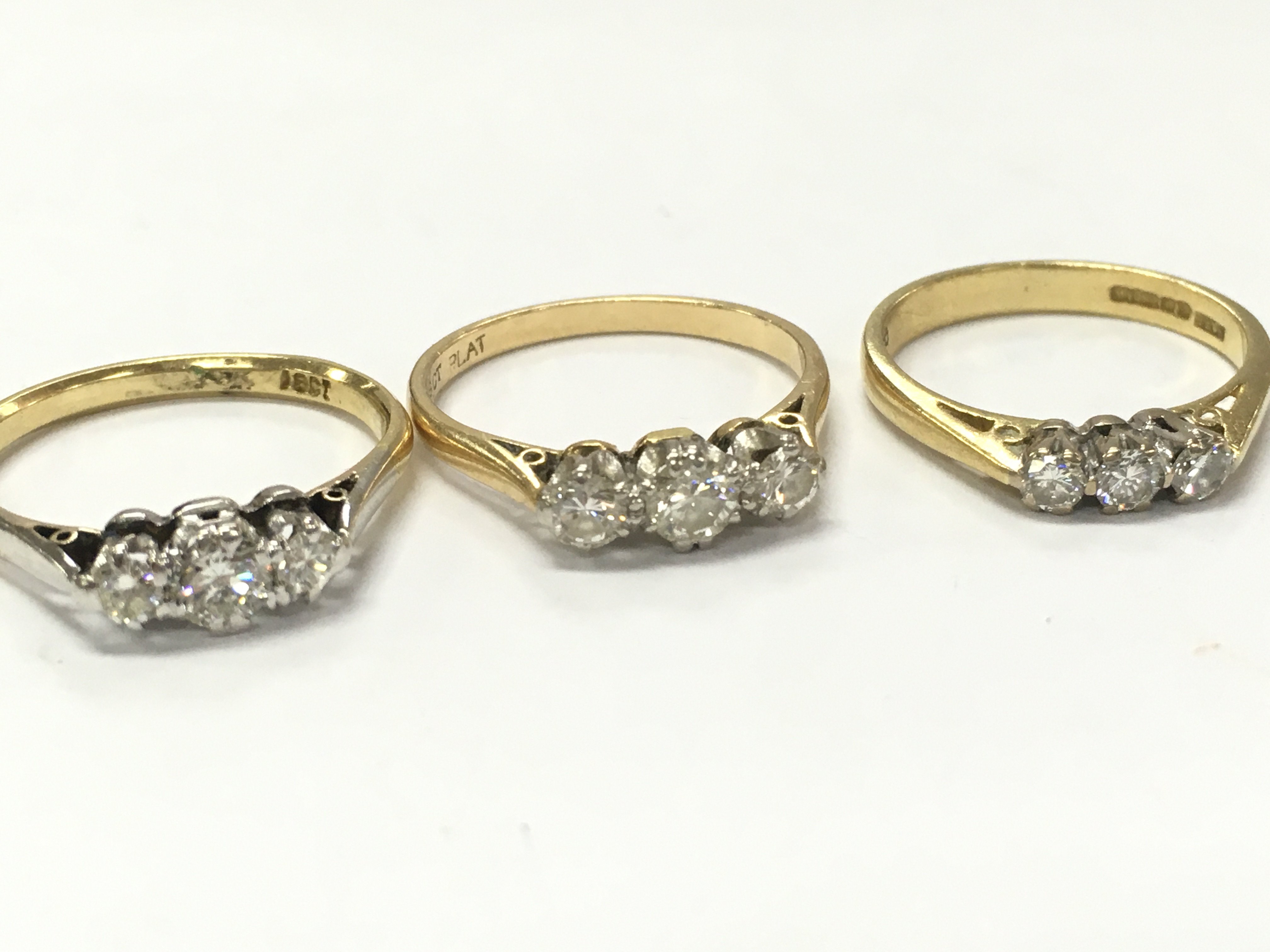 Three 18ct gold three stone diamond rings, 7.4g total weight. Postage category A