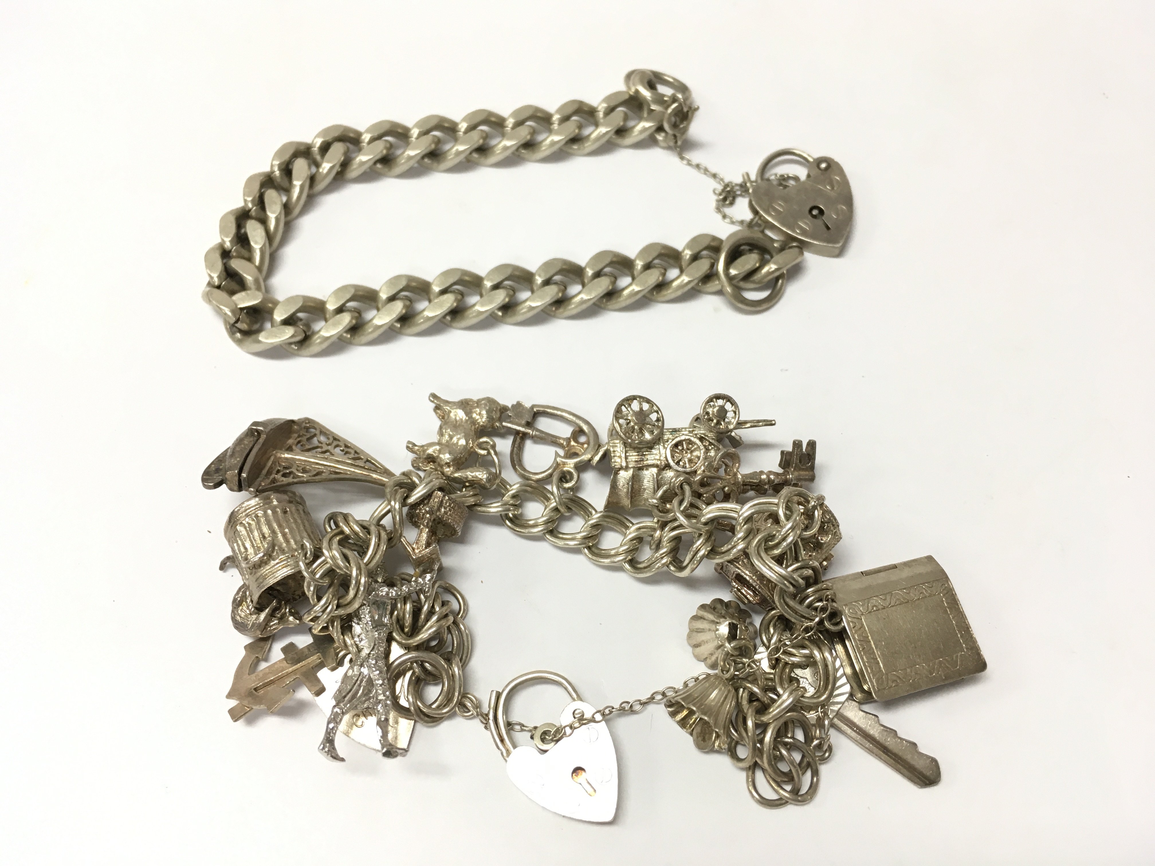 A silver charm bracelet and a silver curb bracelet it&#2013266057۪s a heart lock clasp. Approx weight 79.83 grams.