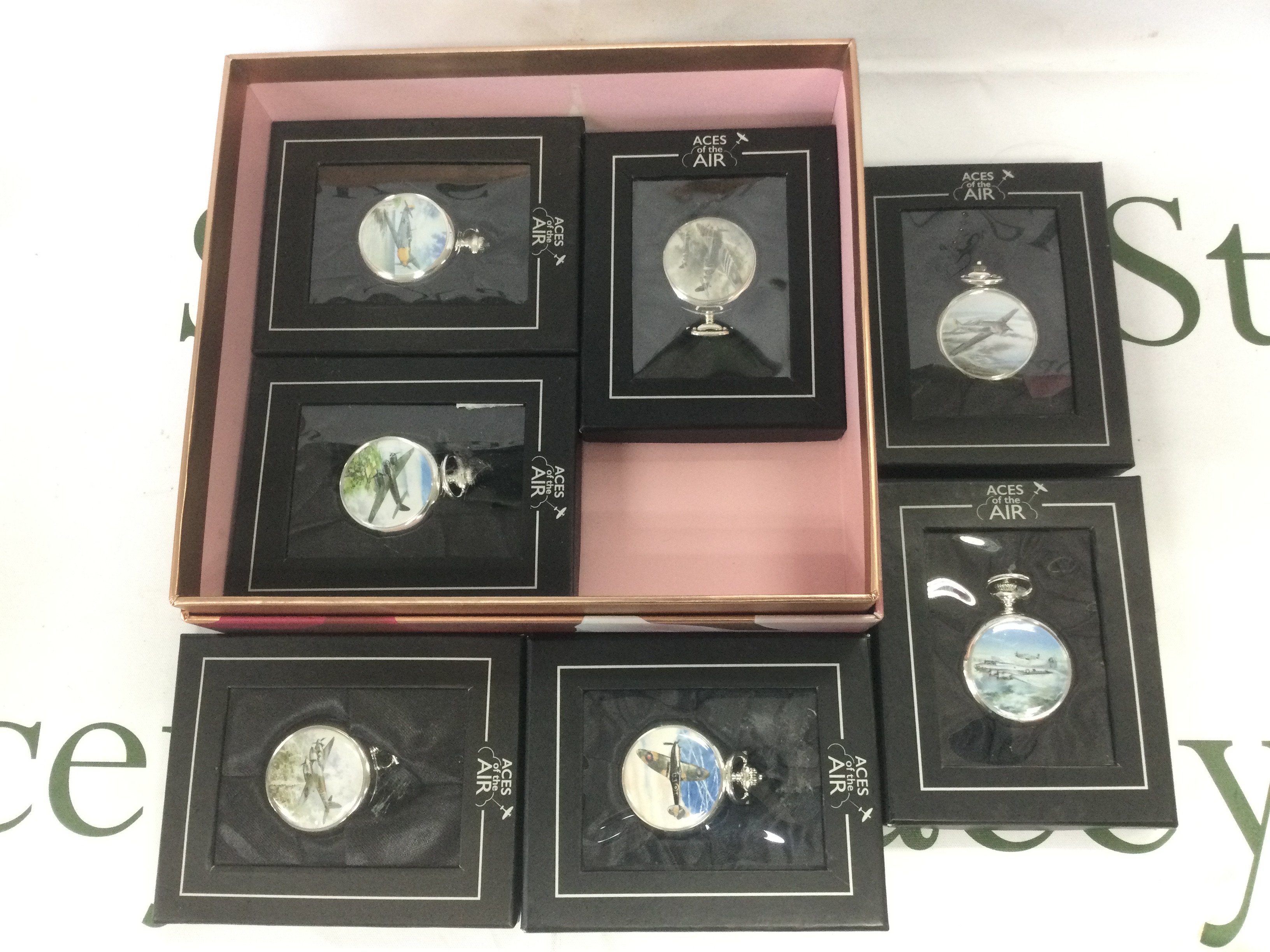 Seven boxed pocket watches decorated with images of WW2 aircraft. Shipping category D.