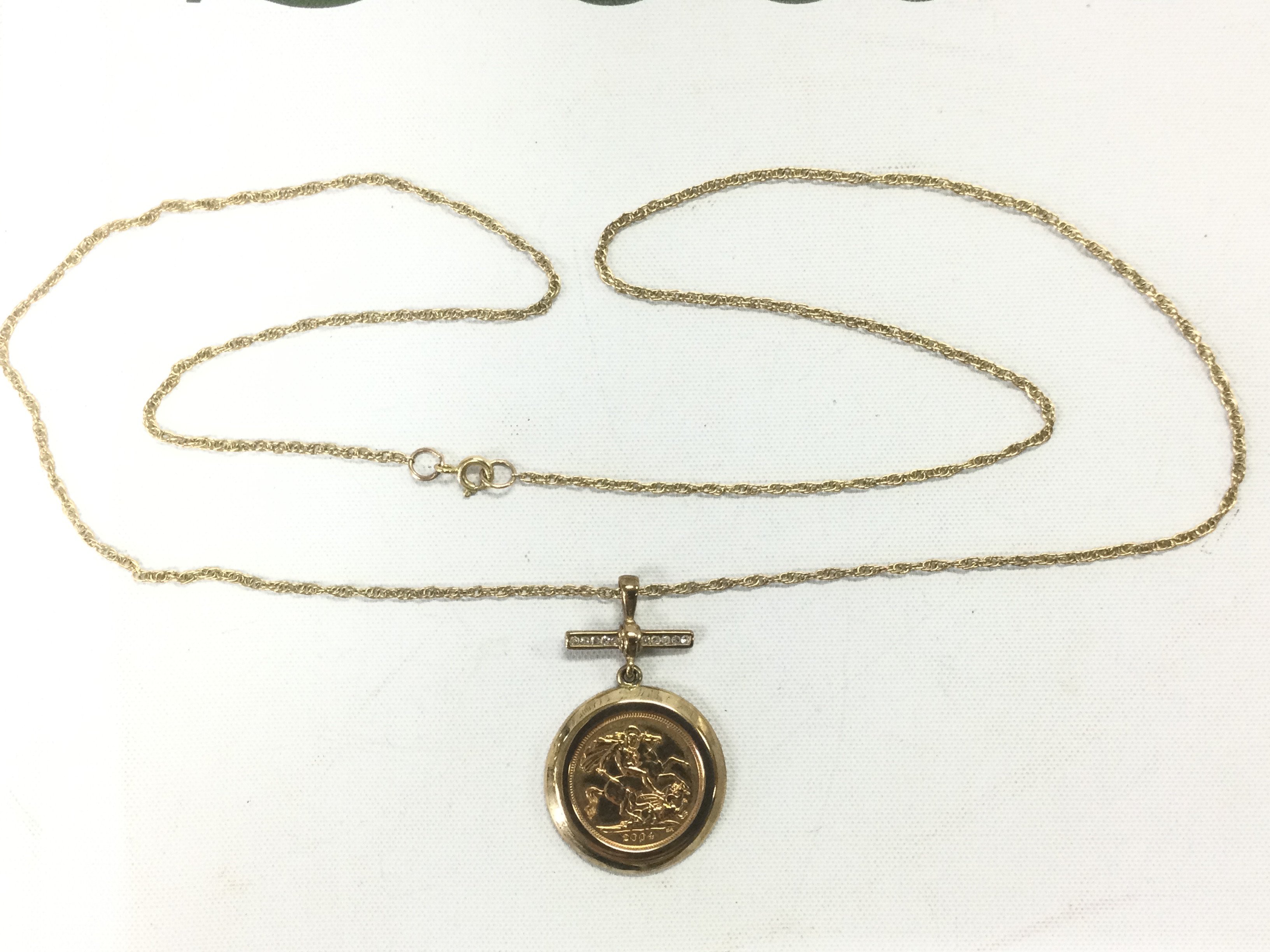 A 2004 gold half sovereign on a chain set with small diamonds, approx 12.7g. Shipping category A.