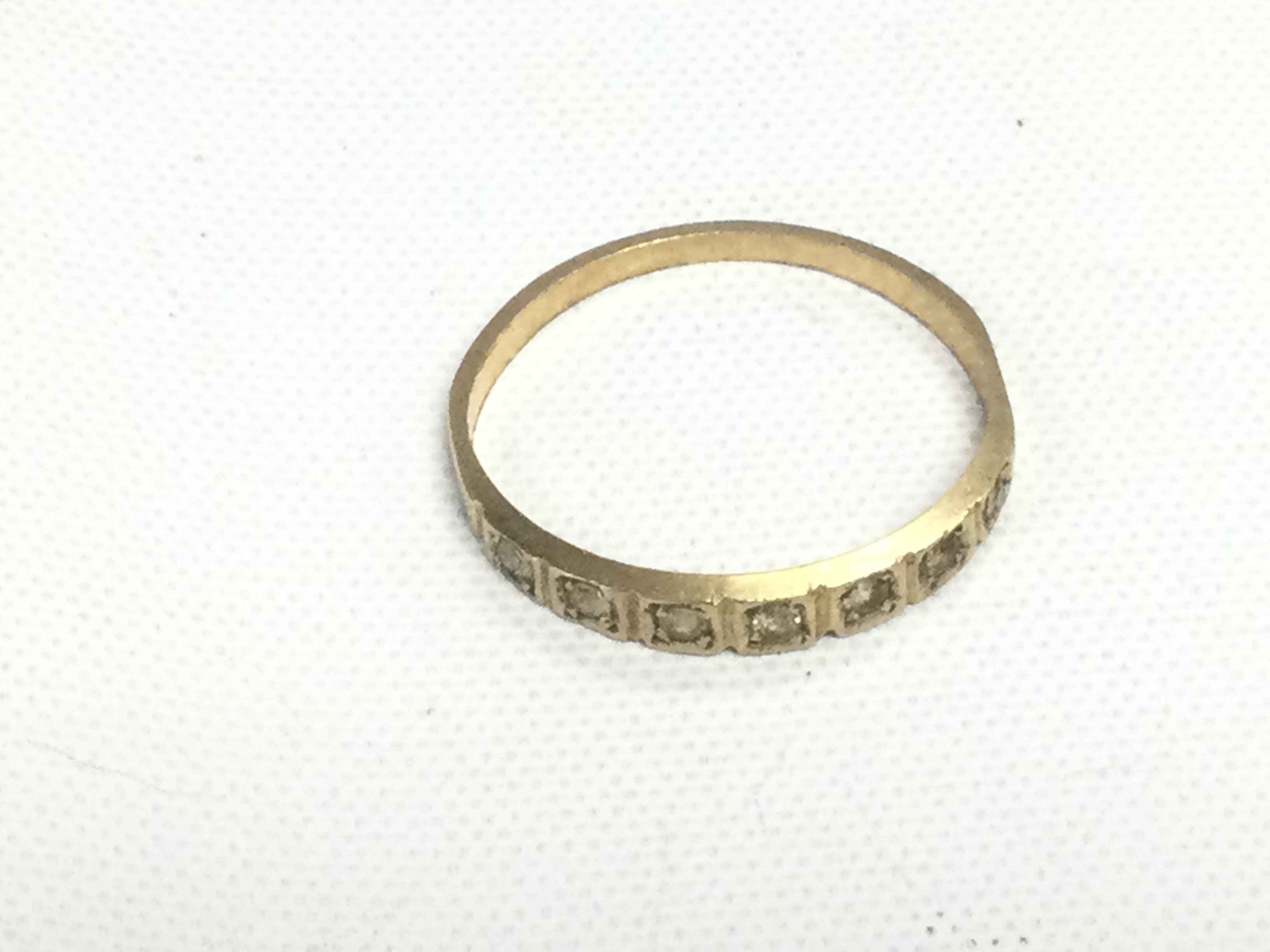 An unmarked yellow metal ring set with clear stones, approx 0.9g and approx size J-K. Shipping category A.