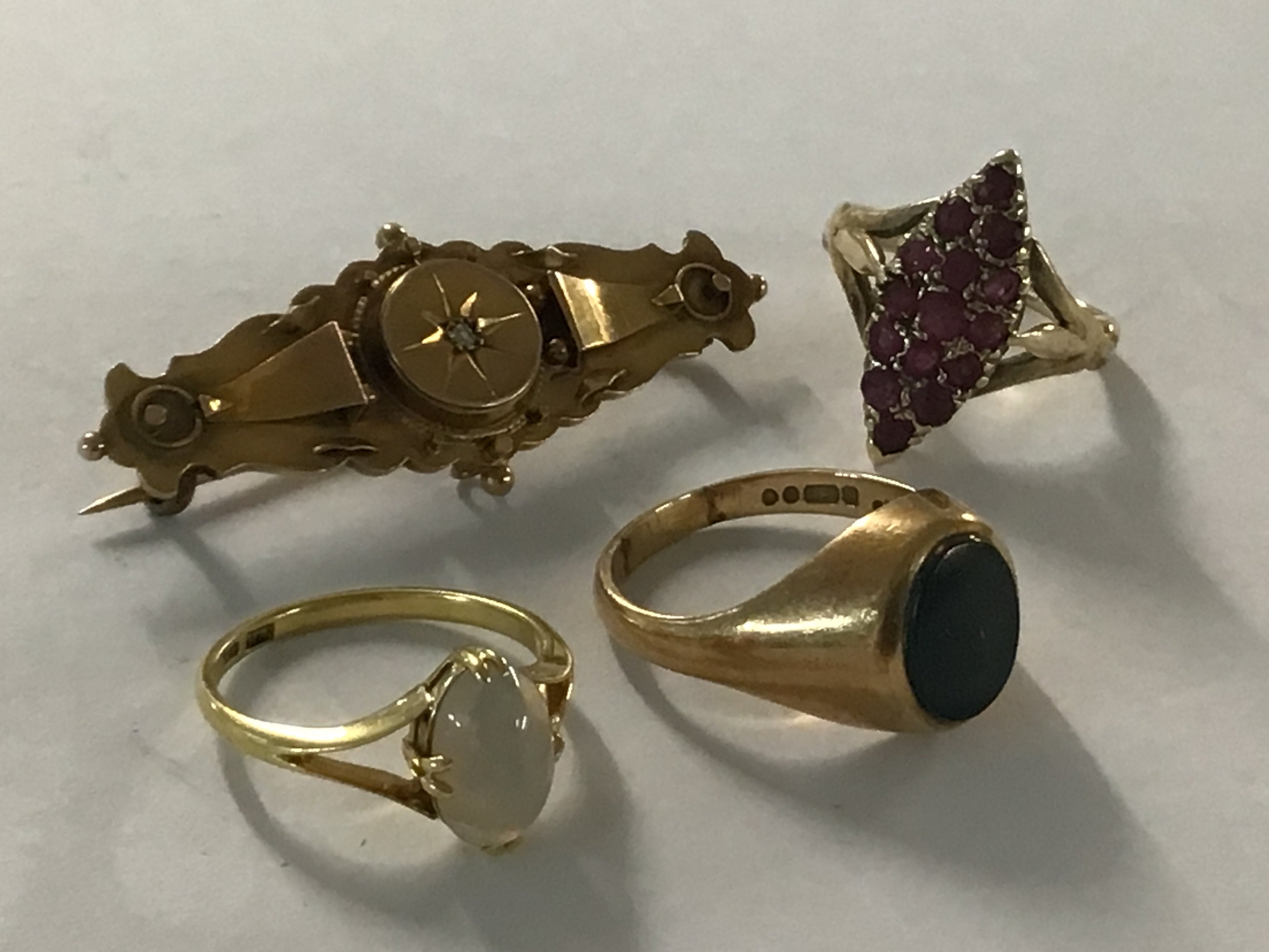 A gold brooch together with three rings including 9ct