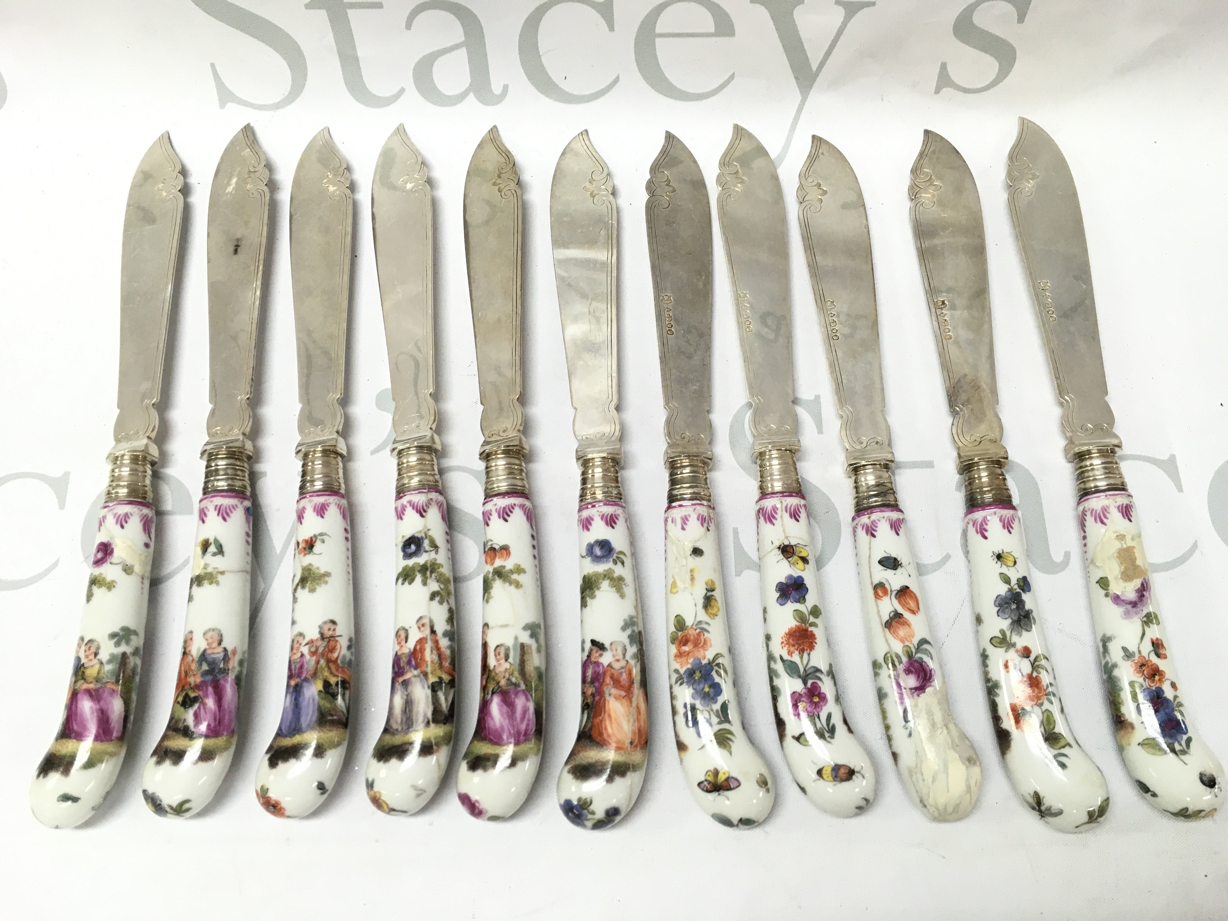 Mid 19th century silver plated knives with ceramic handle design with hand painted decorated with classical style figures and with the other side flowers and insects. Damaged and restored. This lot cannot be posted