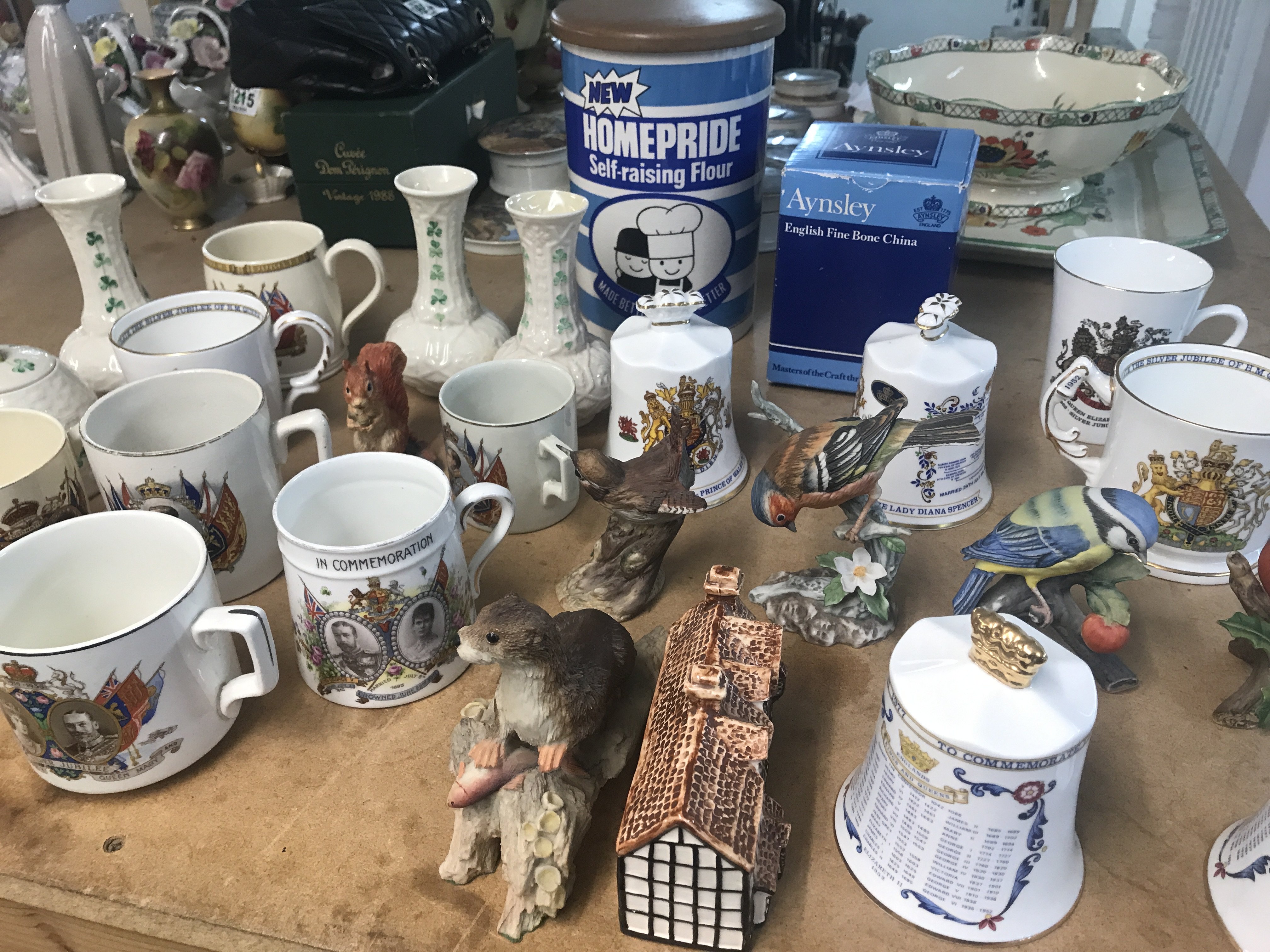 A collection of ceramics including commemorative bells animals figures and Belleek vases .