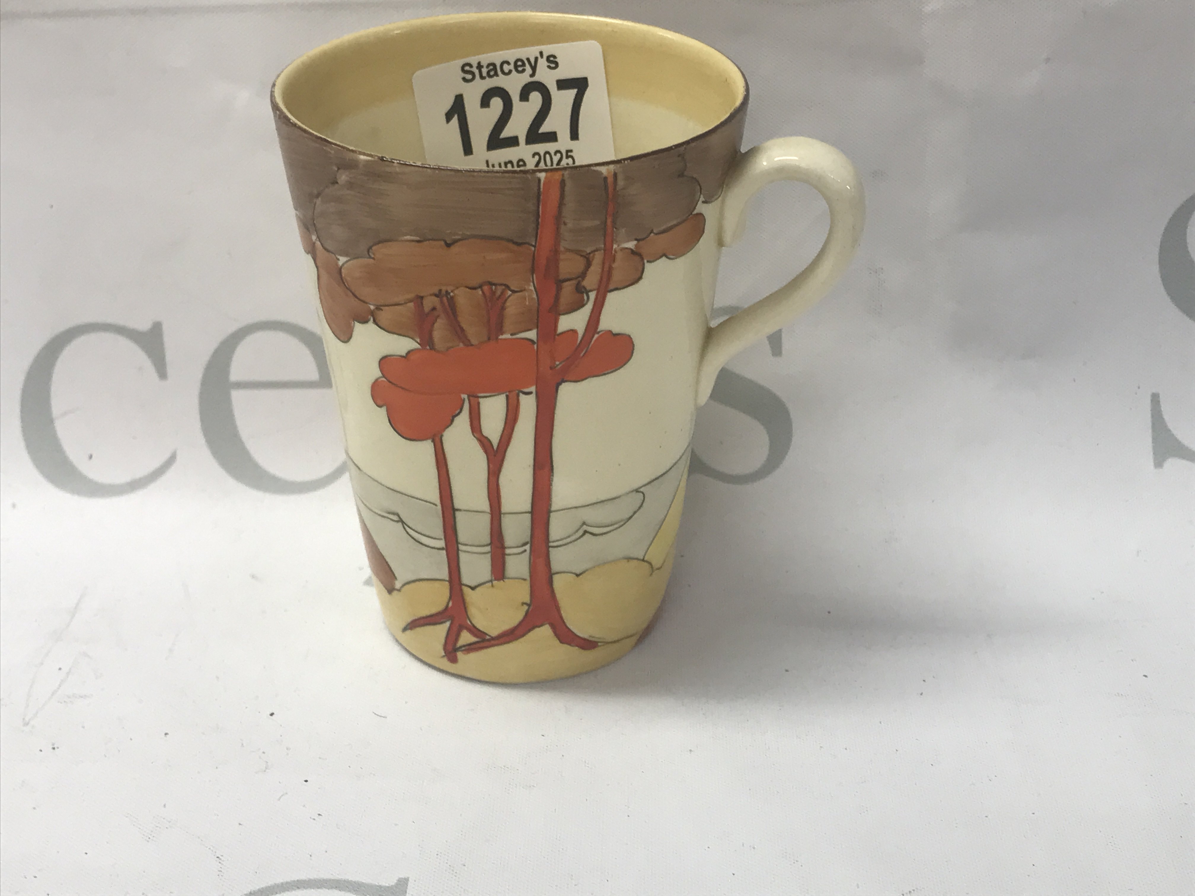 A Clarice Cliff mug decorated with orange trees.