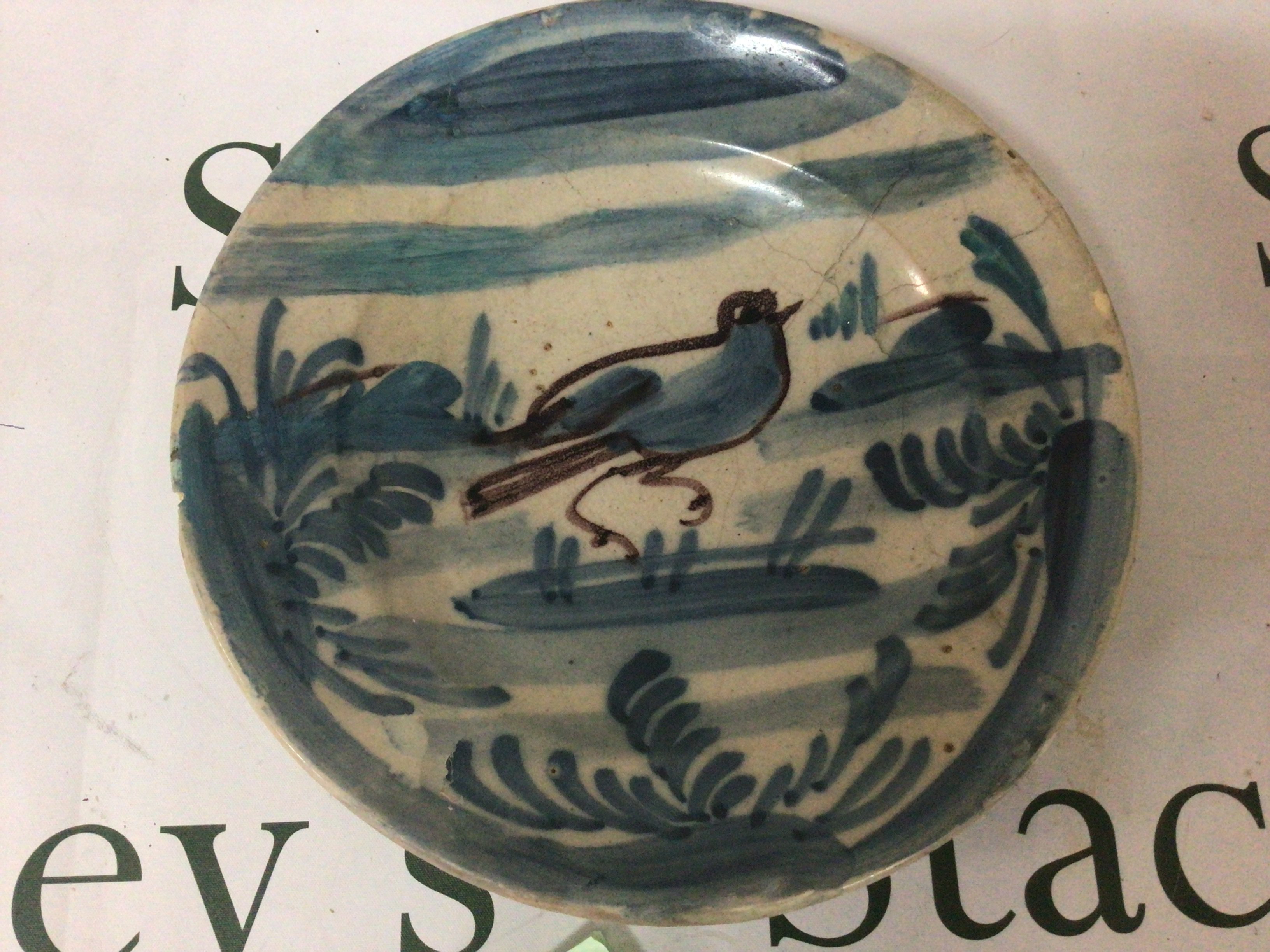 An Antique Continental 18th or early 19th century slip decorated ceramic dish the centre with a nave bird amongst foliage. Some minor damage in keeping with age