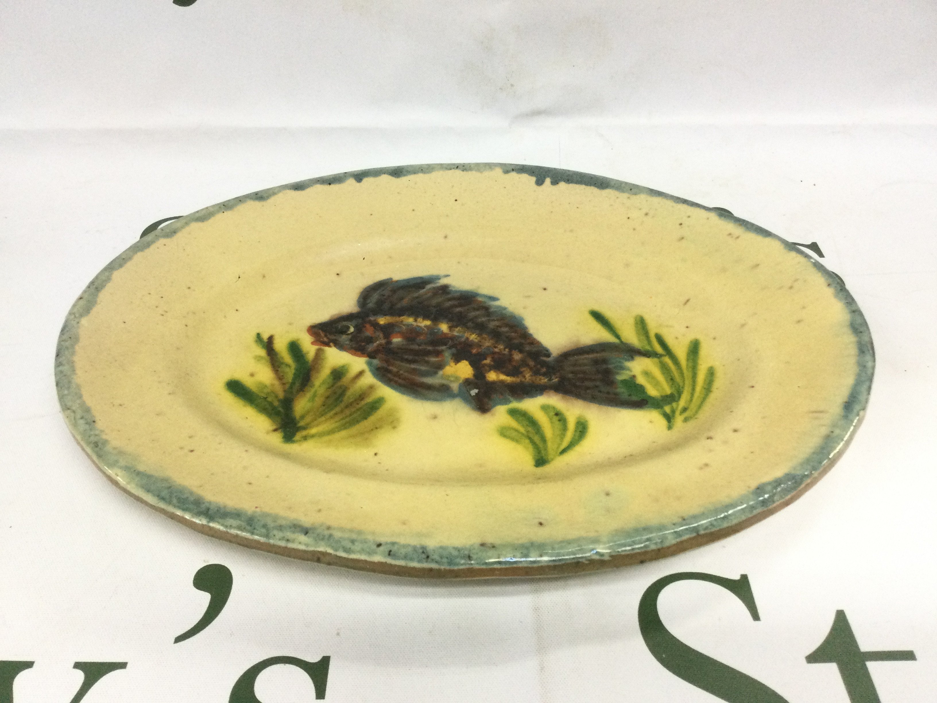 An oval shaped slipware dish decorated with a fish, approx length 26cm. Shipping category D.