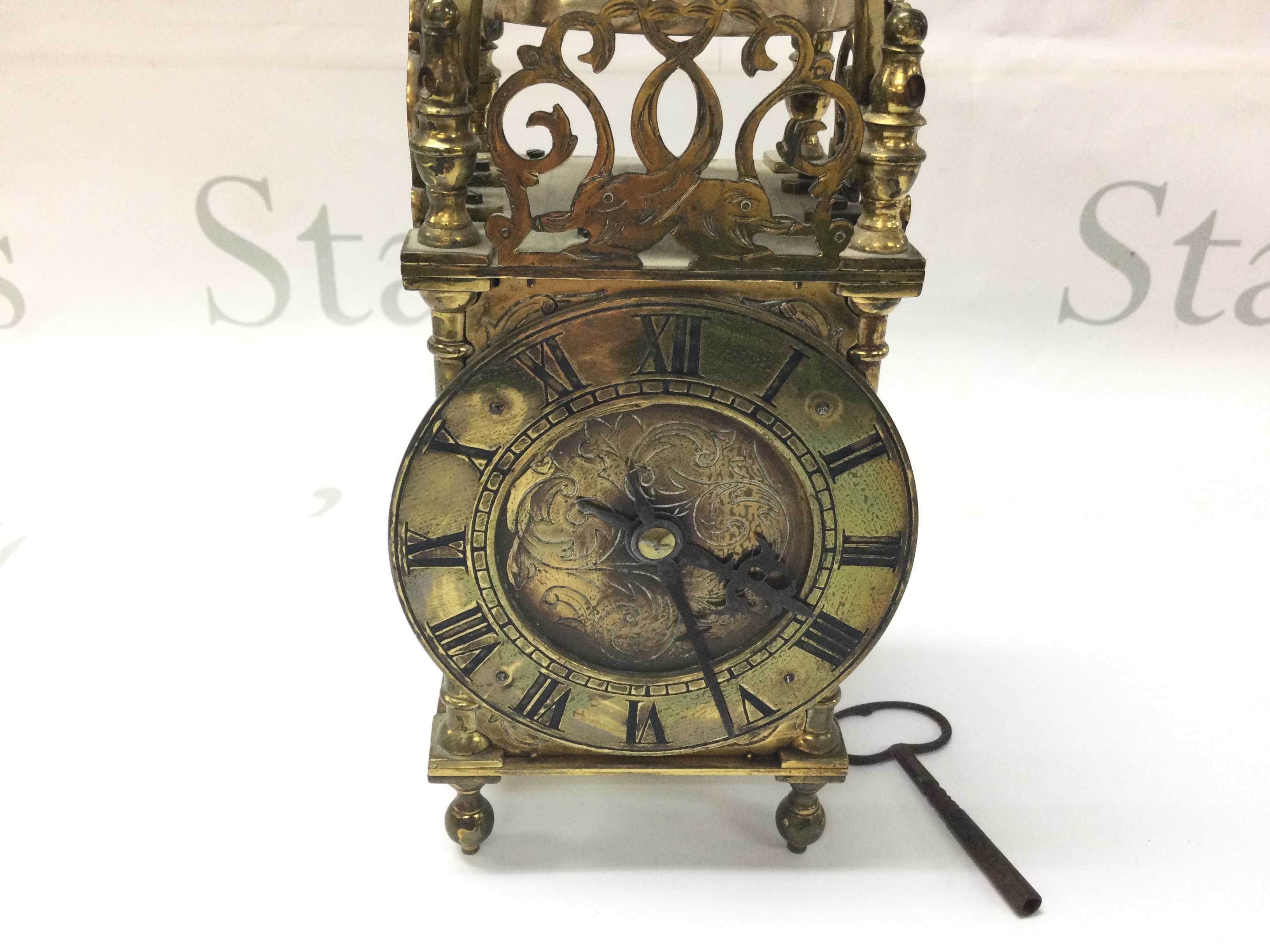 A brass lantern clock. Winds and runs. Approximately 21cm tall.