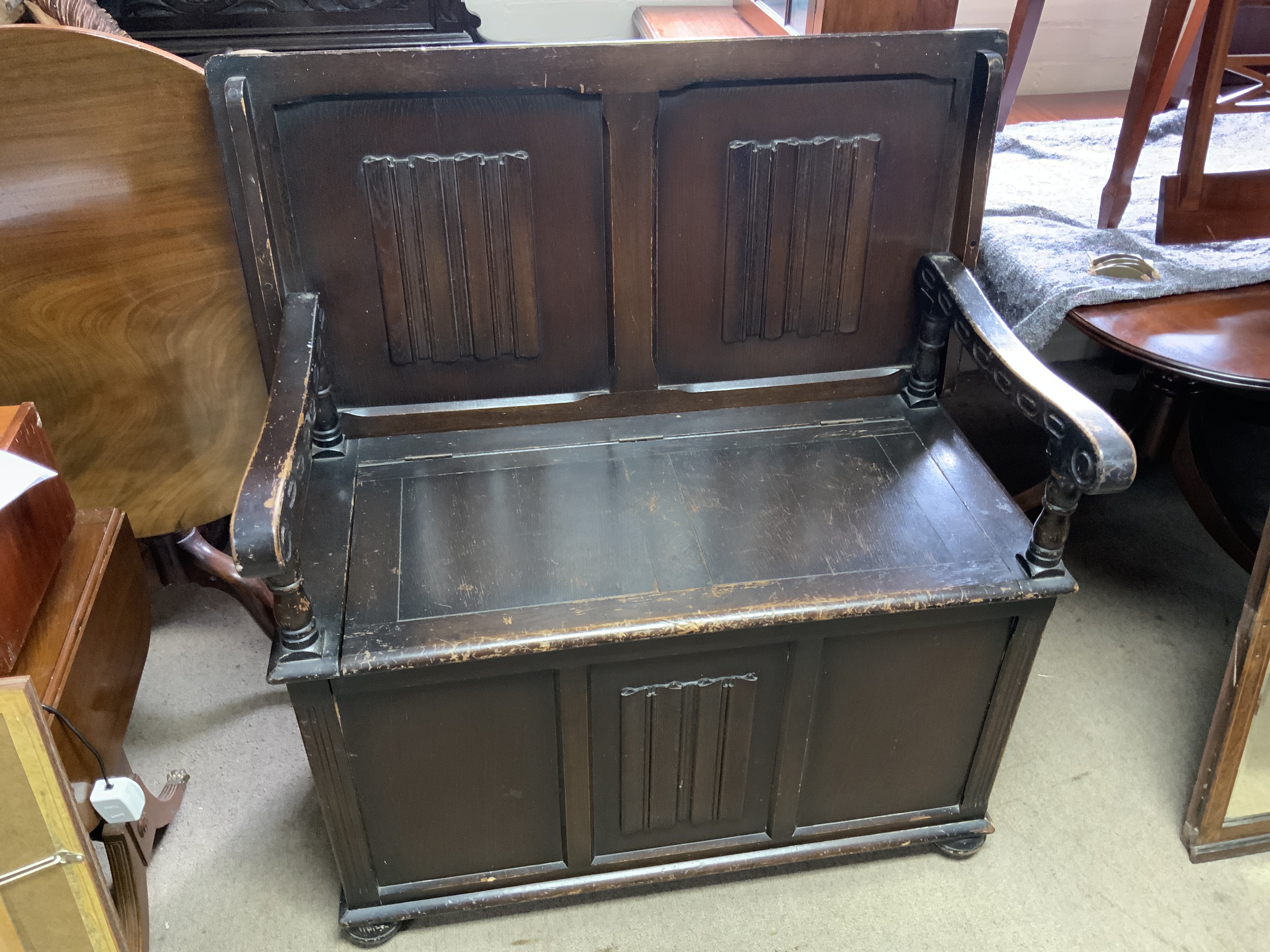 A small oak monks bench with linen fold decoration.
