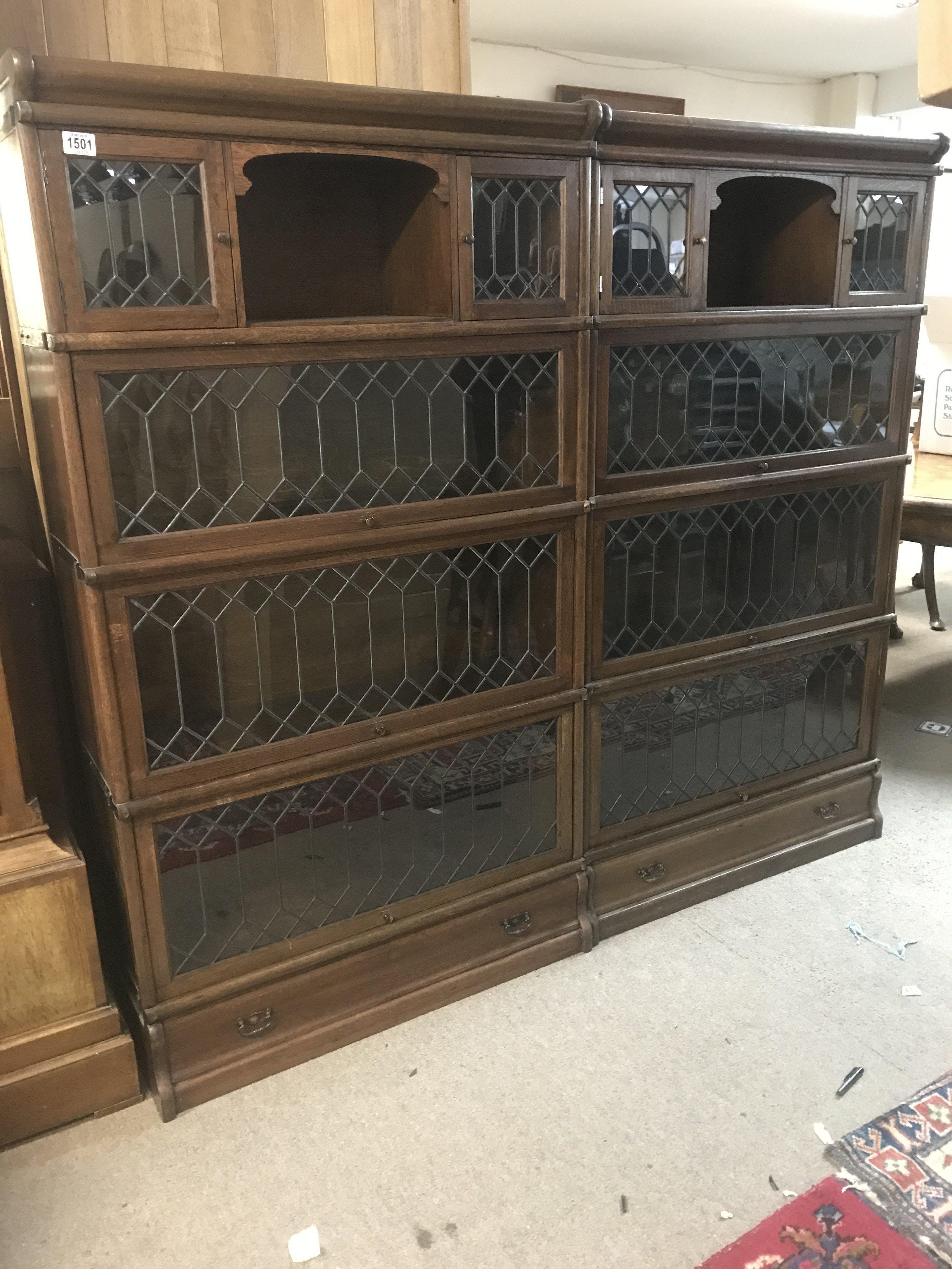 A pair of four tier oak lead light globe wernicke bookcases with single drawer to the base .