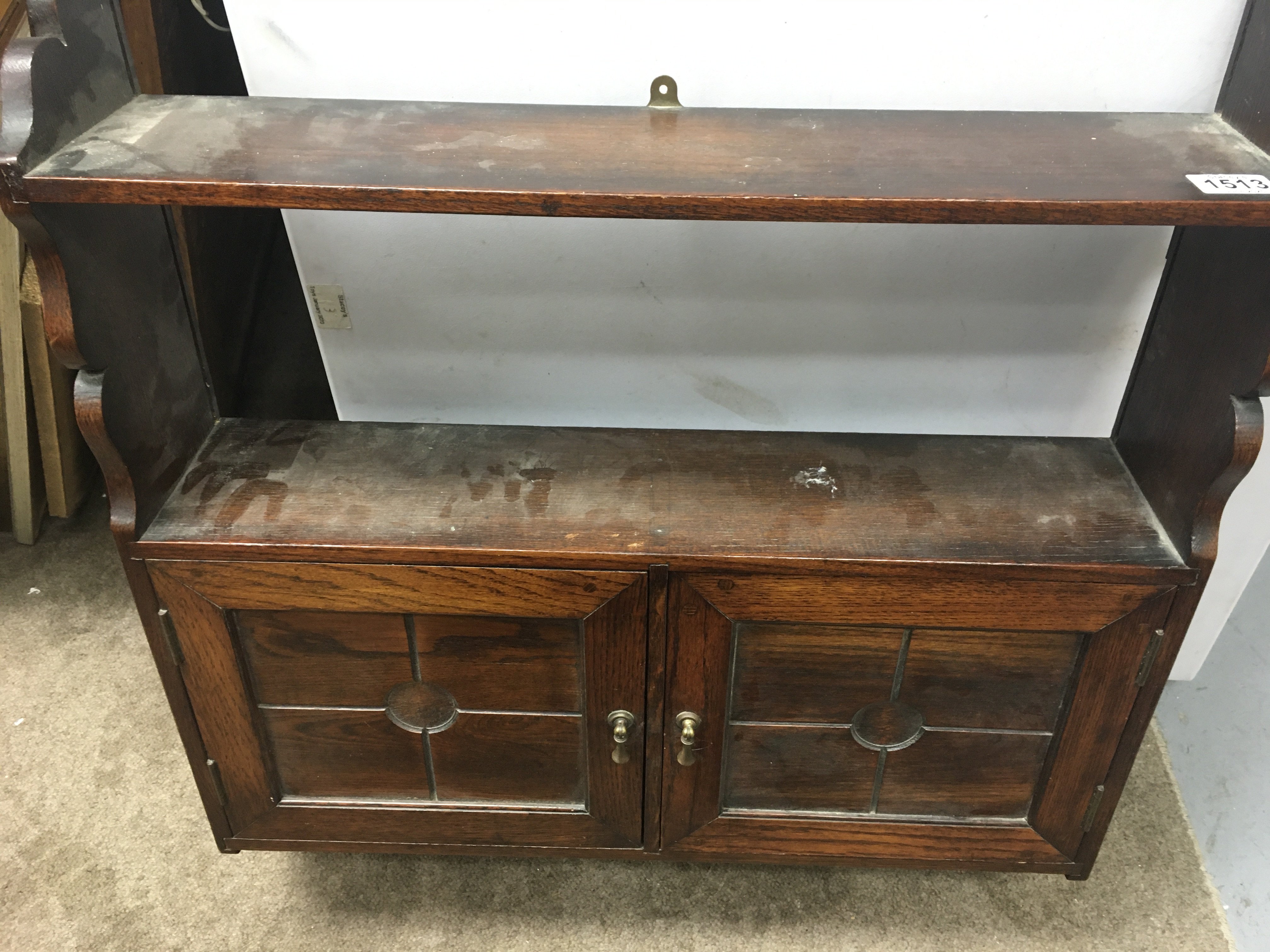 A oak hanging wall cabinet fitted with a pair of paneled doors .
