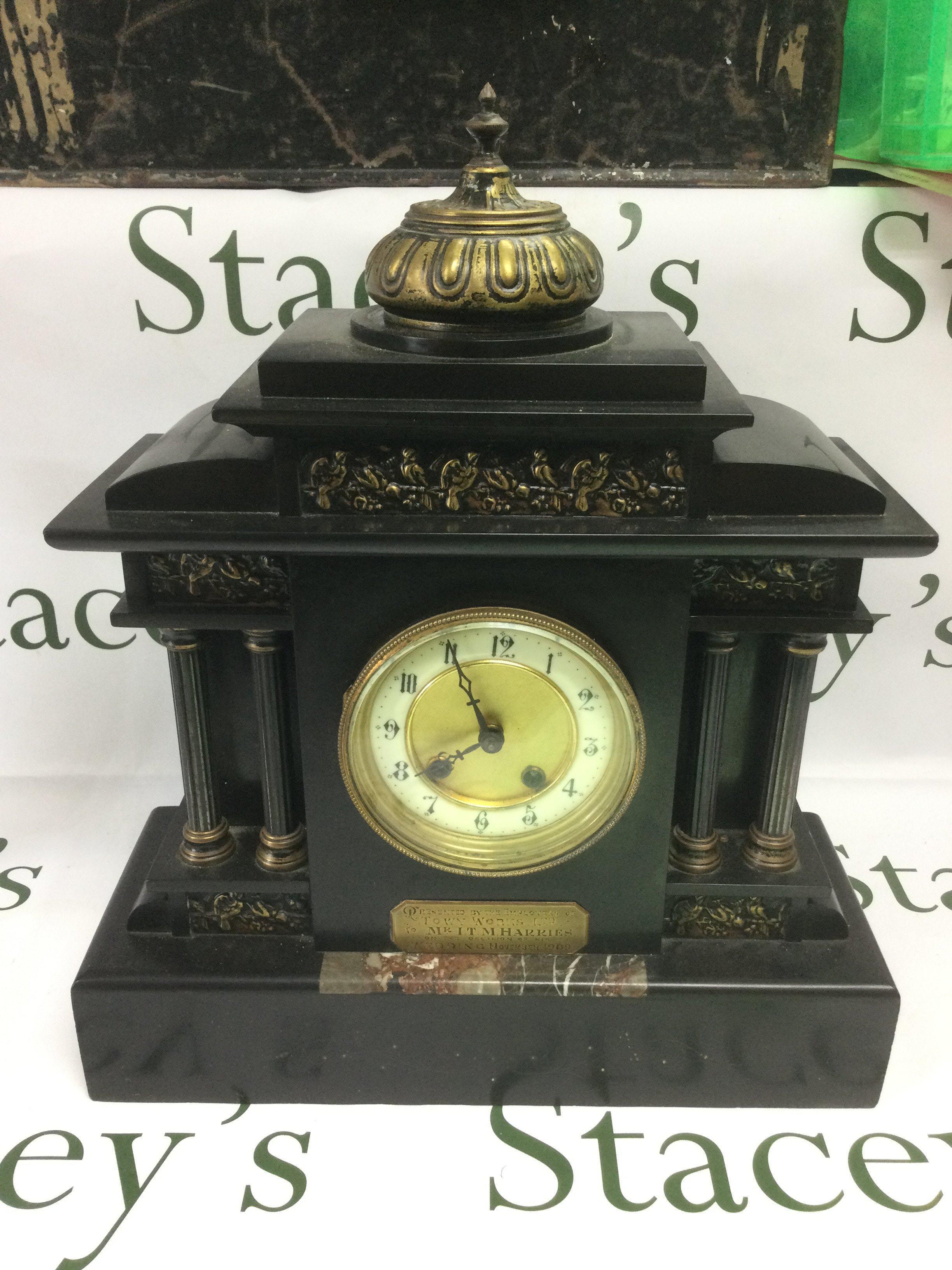 A slate mantle clock with decorative panels and Corinthian column supports. Shipping category D.