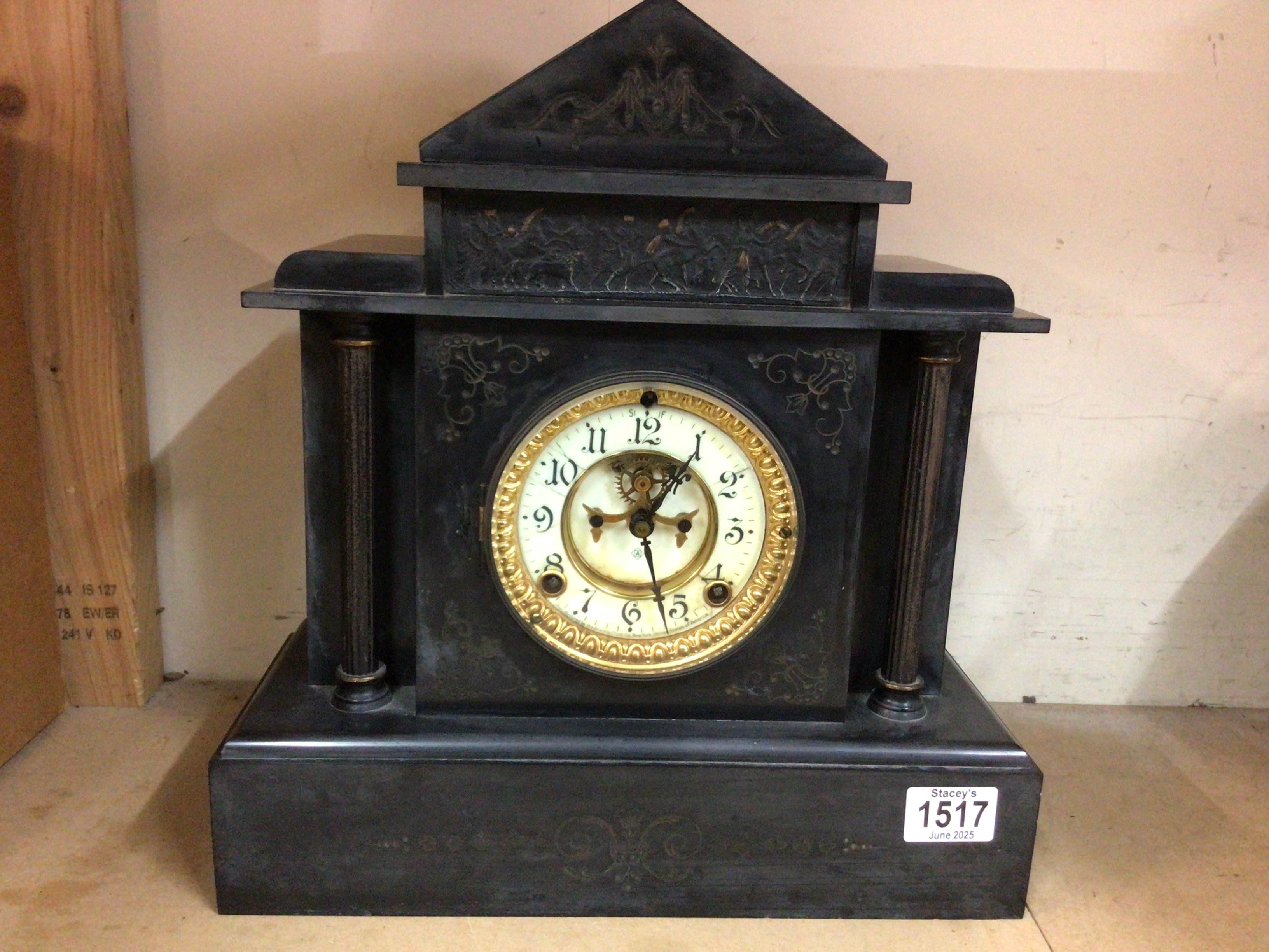 A black slate mantel clock having Roman numerals and visible escapement