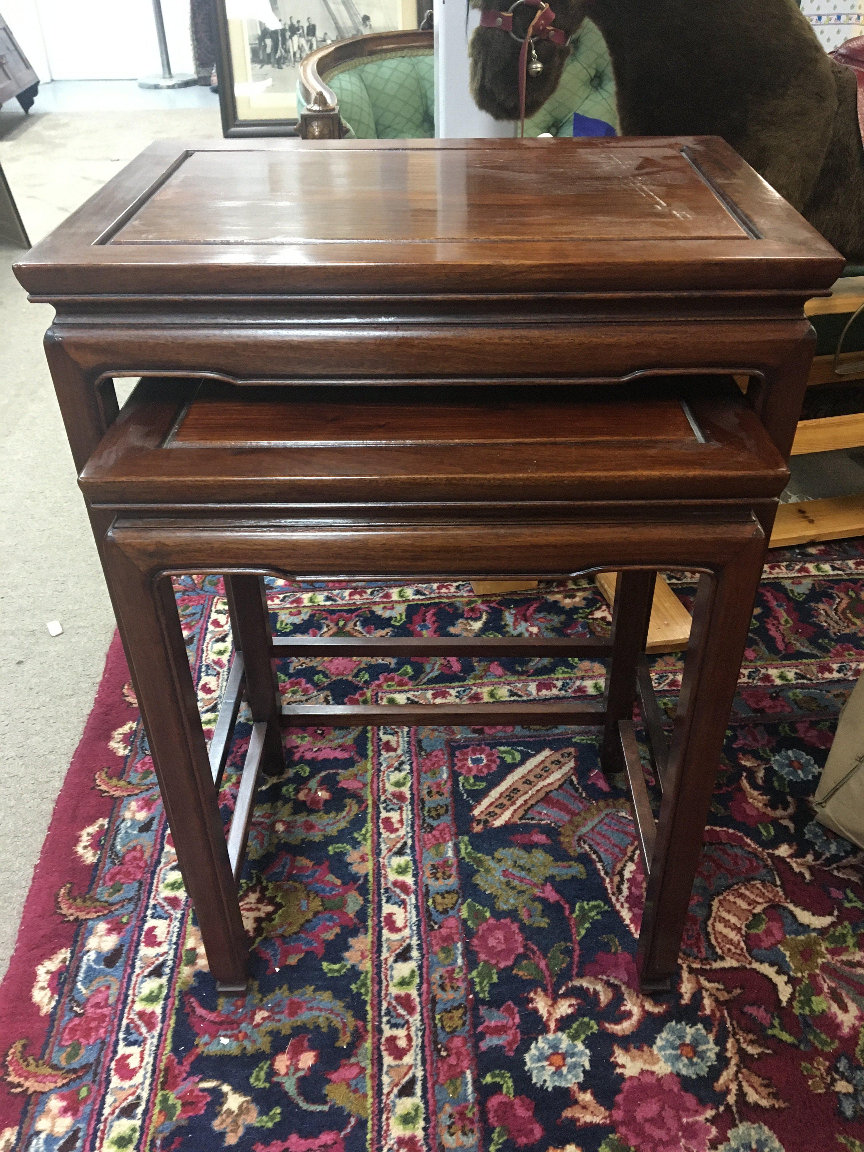 A nest of two mahogany occasional tables .