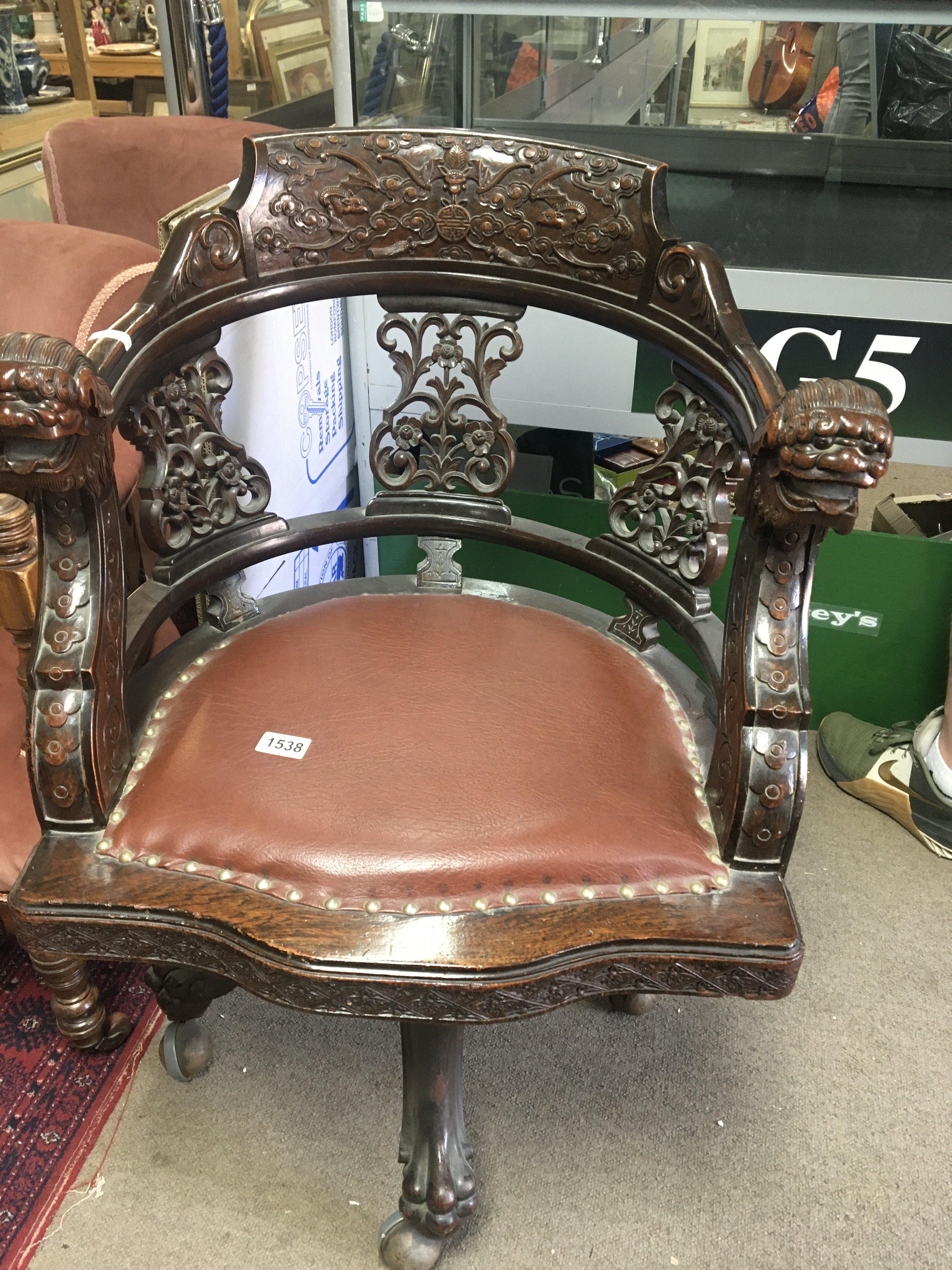 A Chinese office swivel chair carved with dragon heads flowers and foliage.