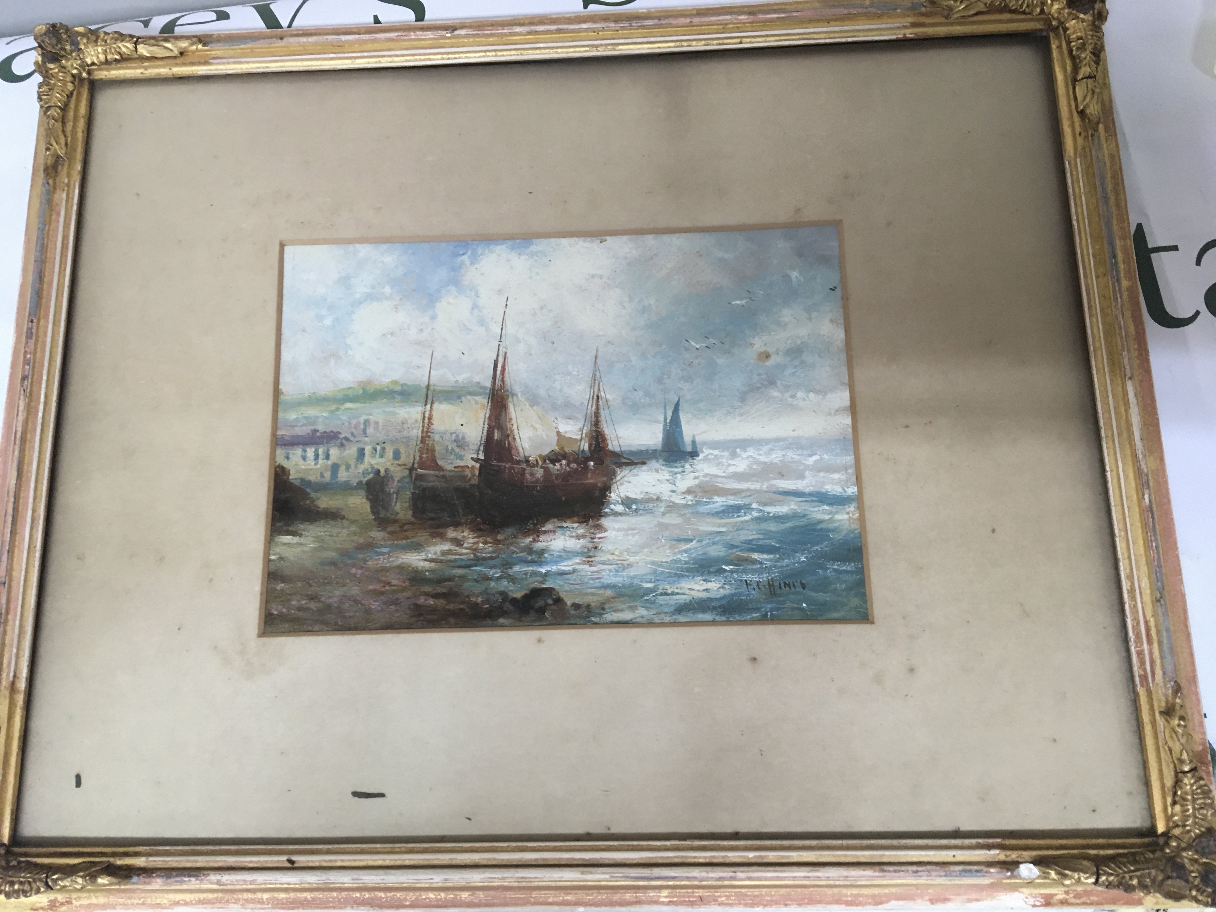 A framed oil moored sailing boats with figures on a shore line. Signed F C Hini&#2013265941s attributed to FC Hines. 25x17cm frame size 50x40cm. NO RESERVE