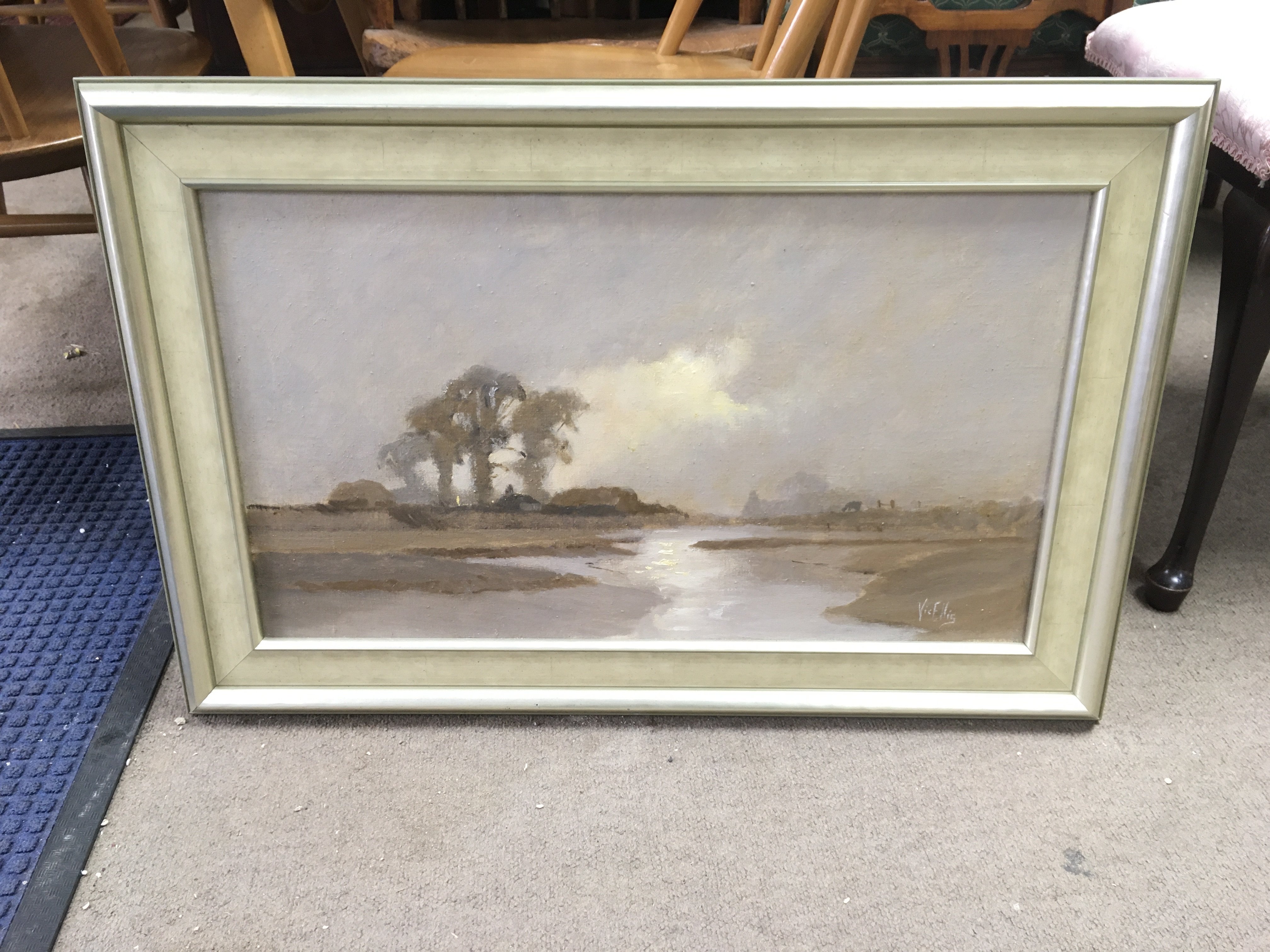 A painting of a countryside view signed Vic Ellis. Approx measurements 75x50cm.