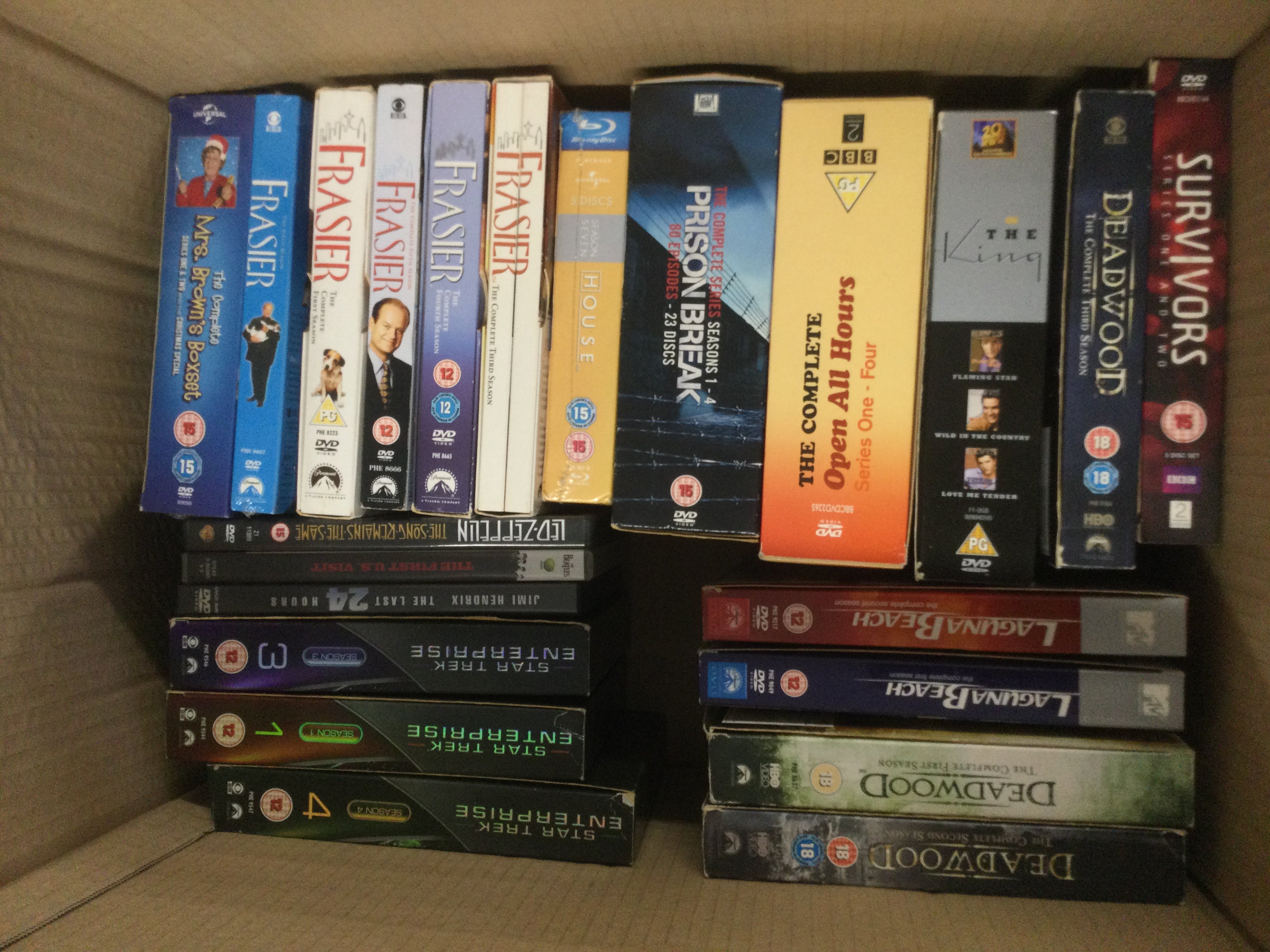 Four boxes of DVDs and VHS tapes comprising various films and TV series including some box sets. Shipping category D. NO RESERVE