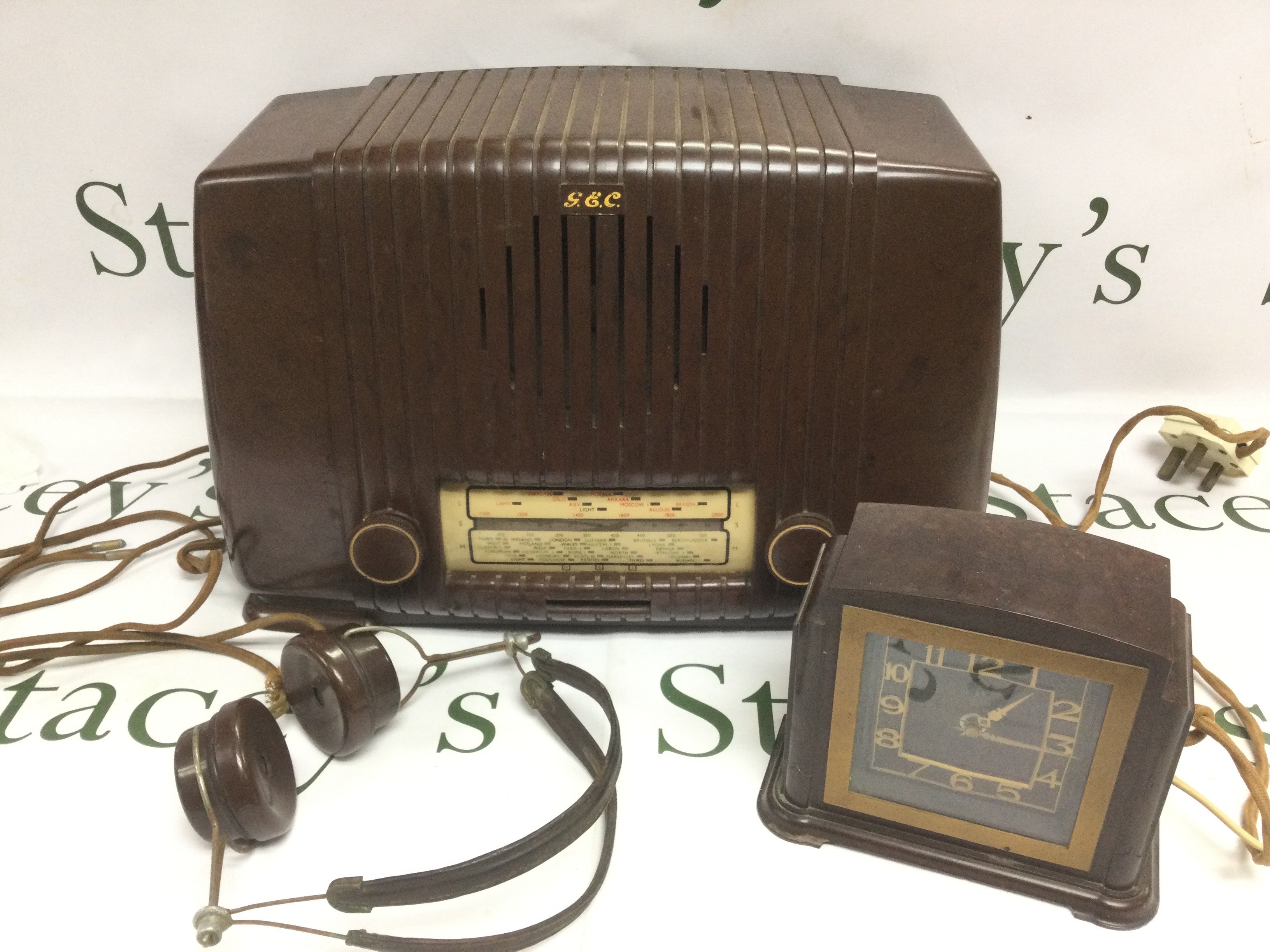Three bakelite items comprising a radio, clock and headphones. Shipping category D.