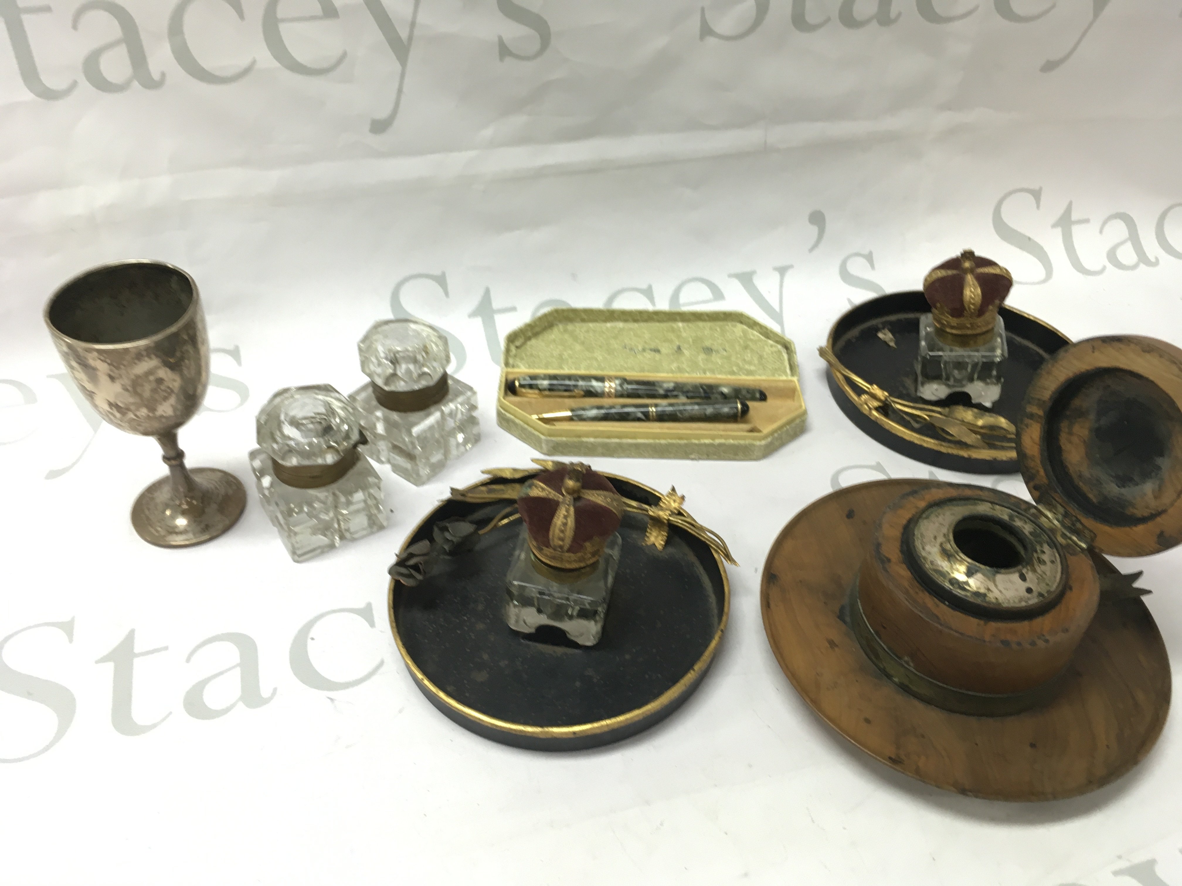 A wooden inkwell, two pairs of inkwells, a hallmarked silver cup and two Unique pens . This lot cannot be posted