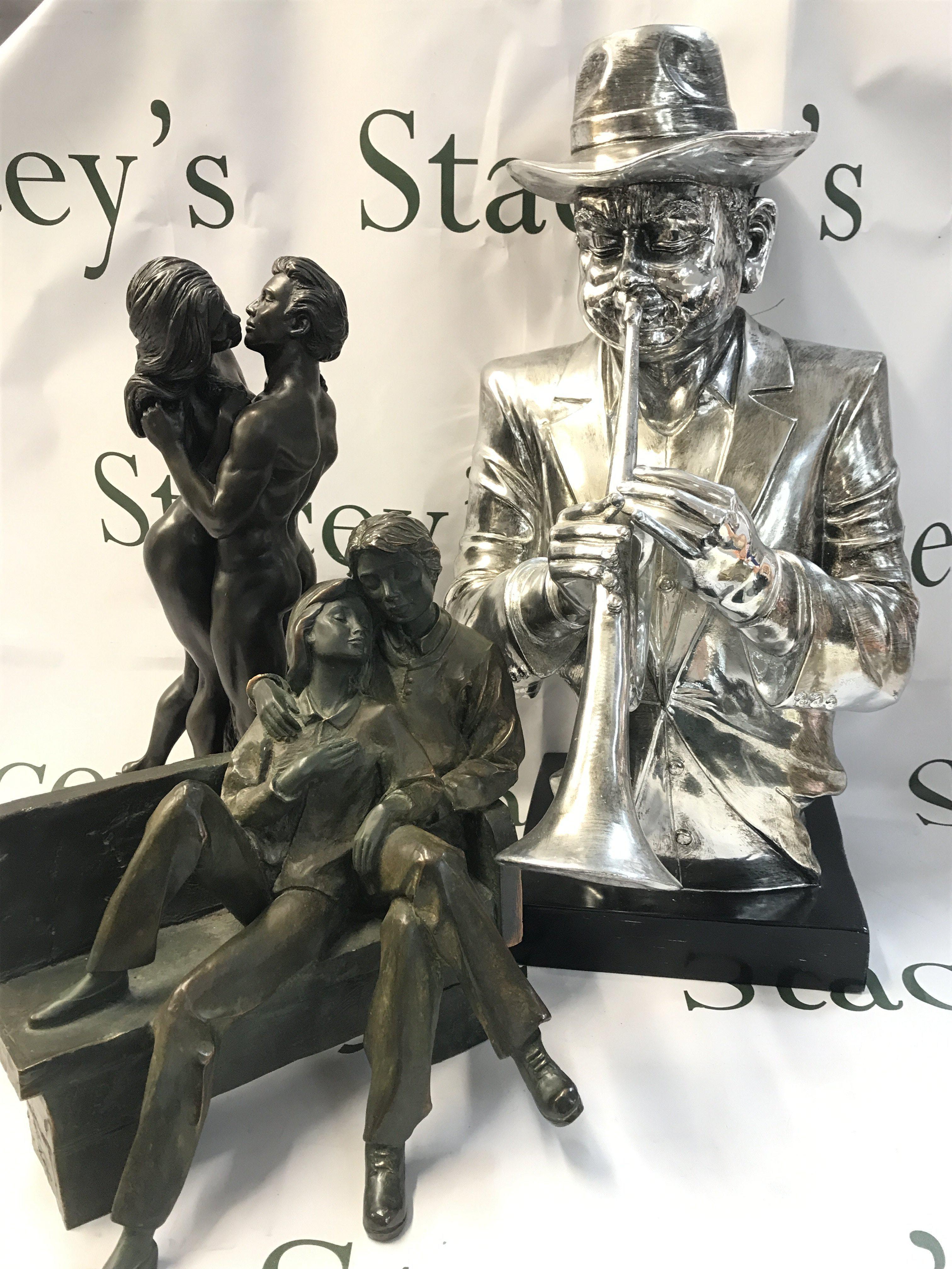 Figures including simulated bronze figure groups of lovers and a trumpet player figure. 26 to 46cm tall. This lot cannot be posted