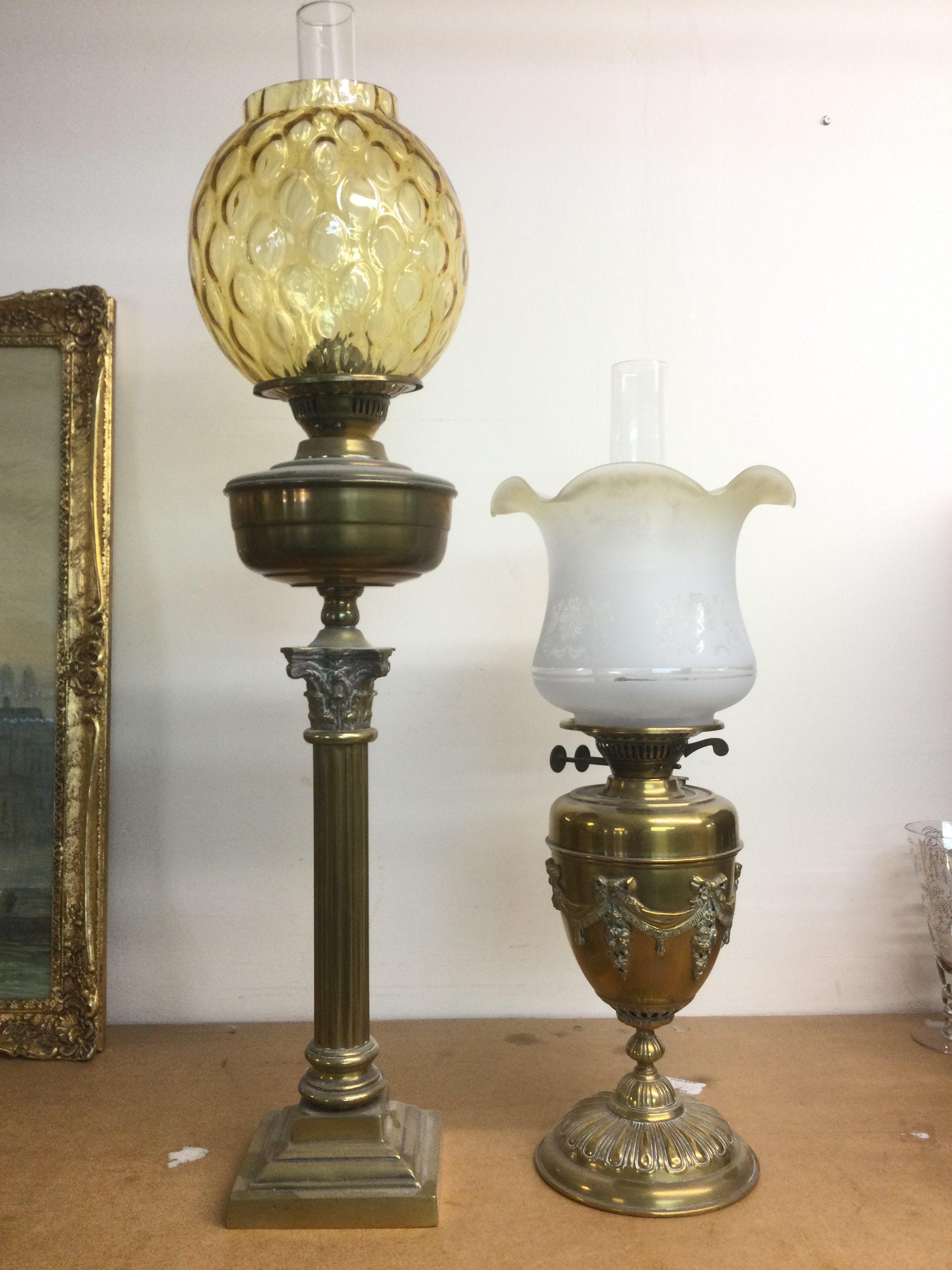 Two oil lamps comprising a Corinthian column example and one with decorative swags. Shipping category D.