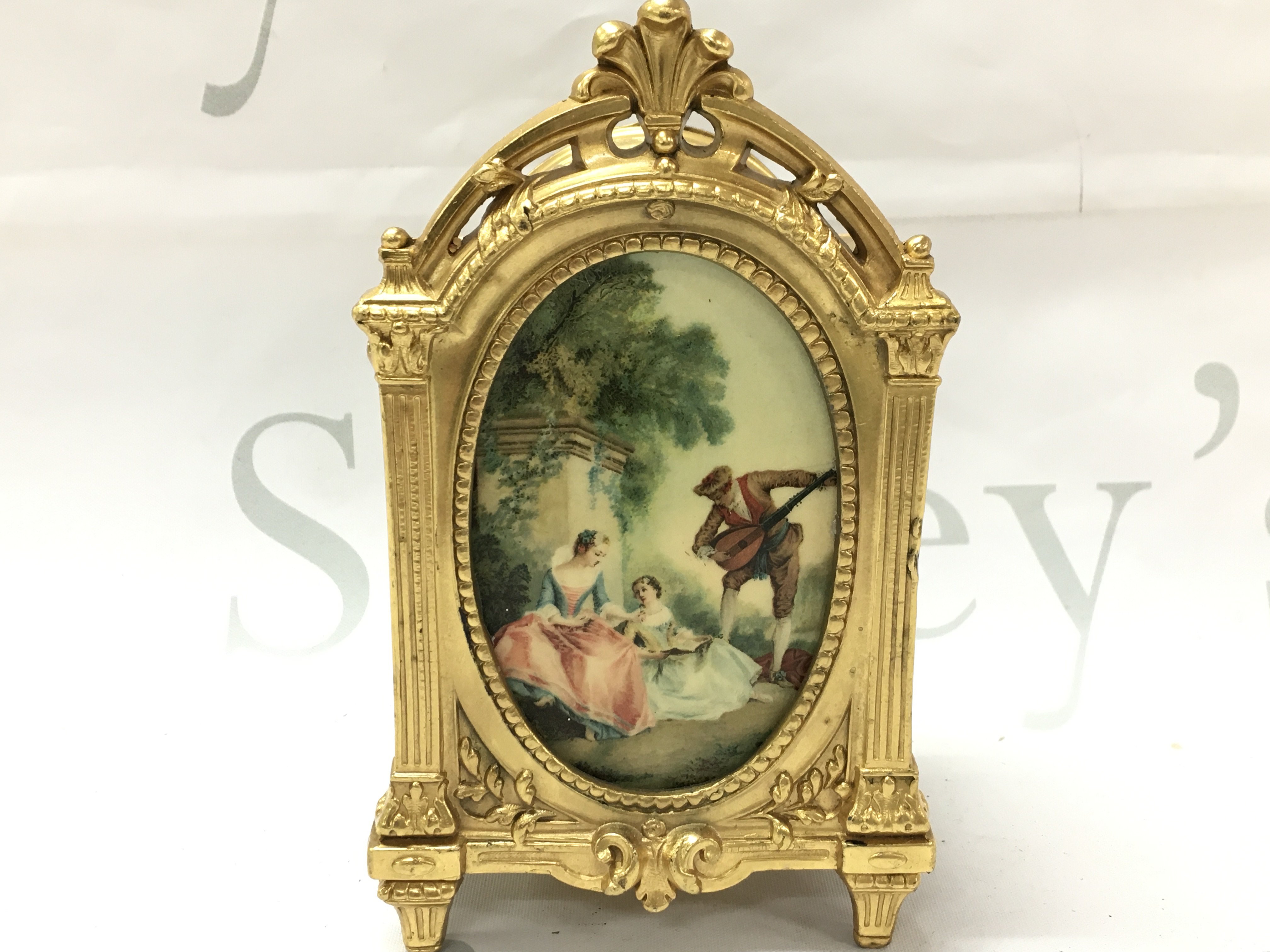 A French gilt trinket box with an oval plaque of classical figure design and embossed floral patterns. (damage to hinge at the door panel). Base marked Depose N.27. 8.5cm wide 15.5cm tall 7cm long. Postage category B