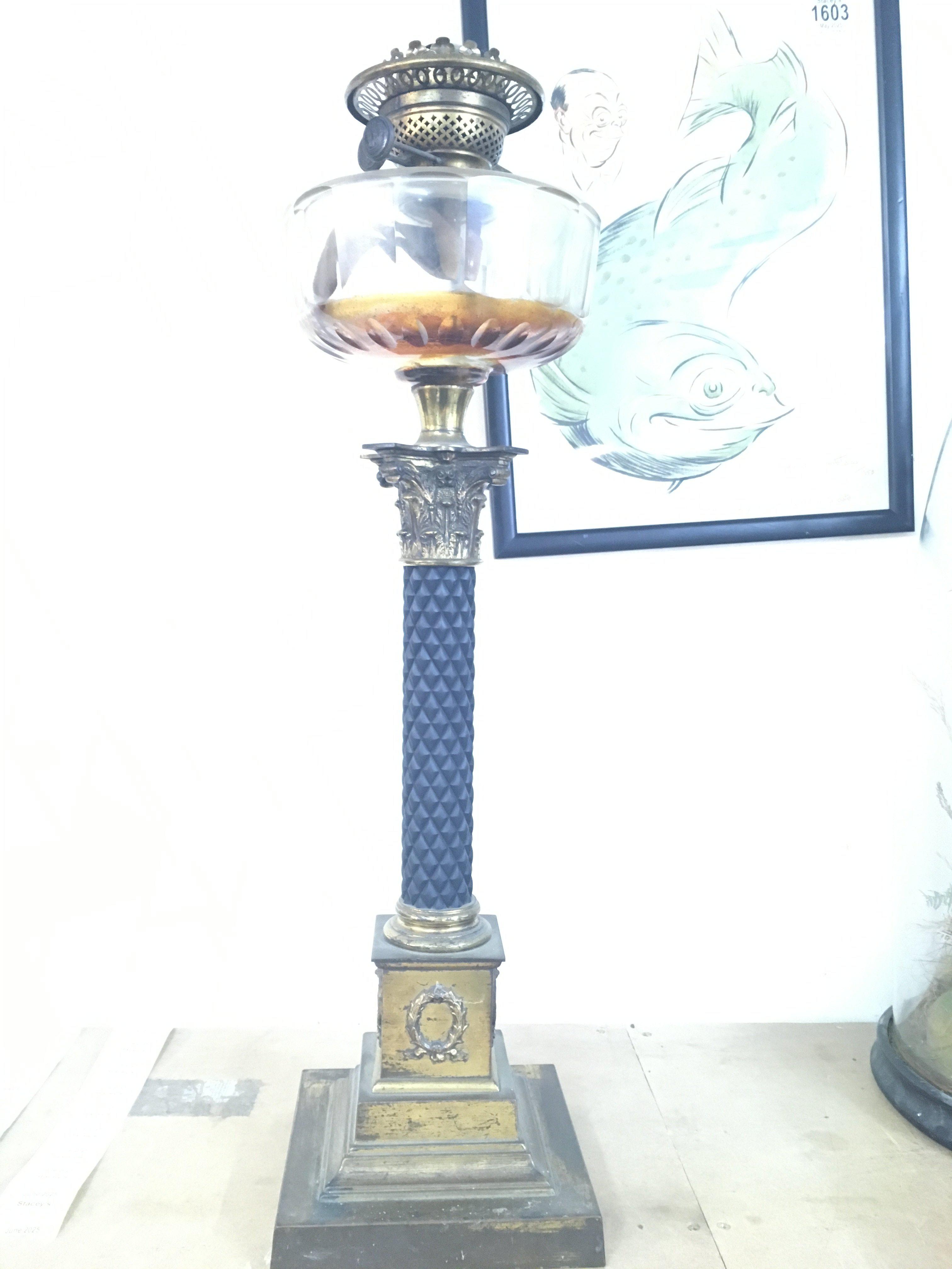 A Victorian brass oil lamp the glass font above a corinthian column .