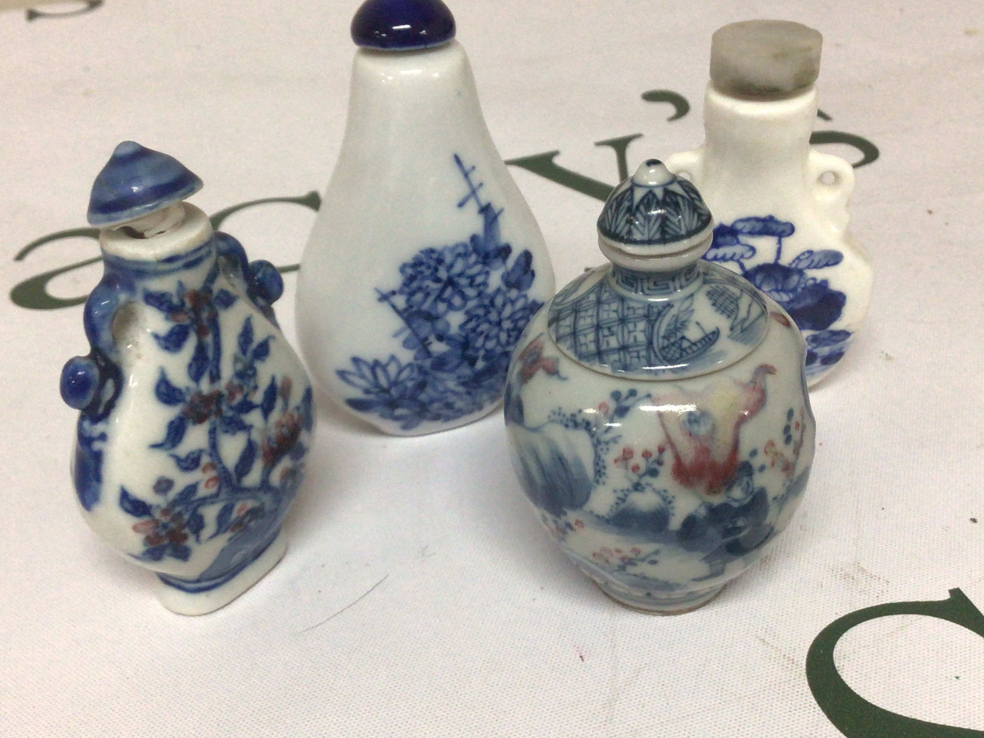 An interesting Chinese porcelain scent bottle with revolving central sections the sides decorated with figures and underglaze iron red with blue Caricature marks to the base and three other blue and white Chinese porcelain scent bottles. (4)