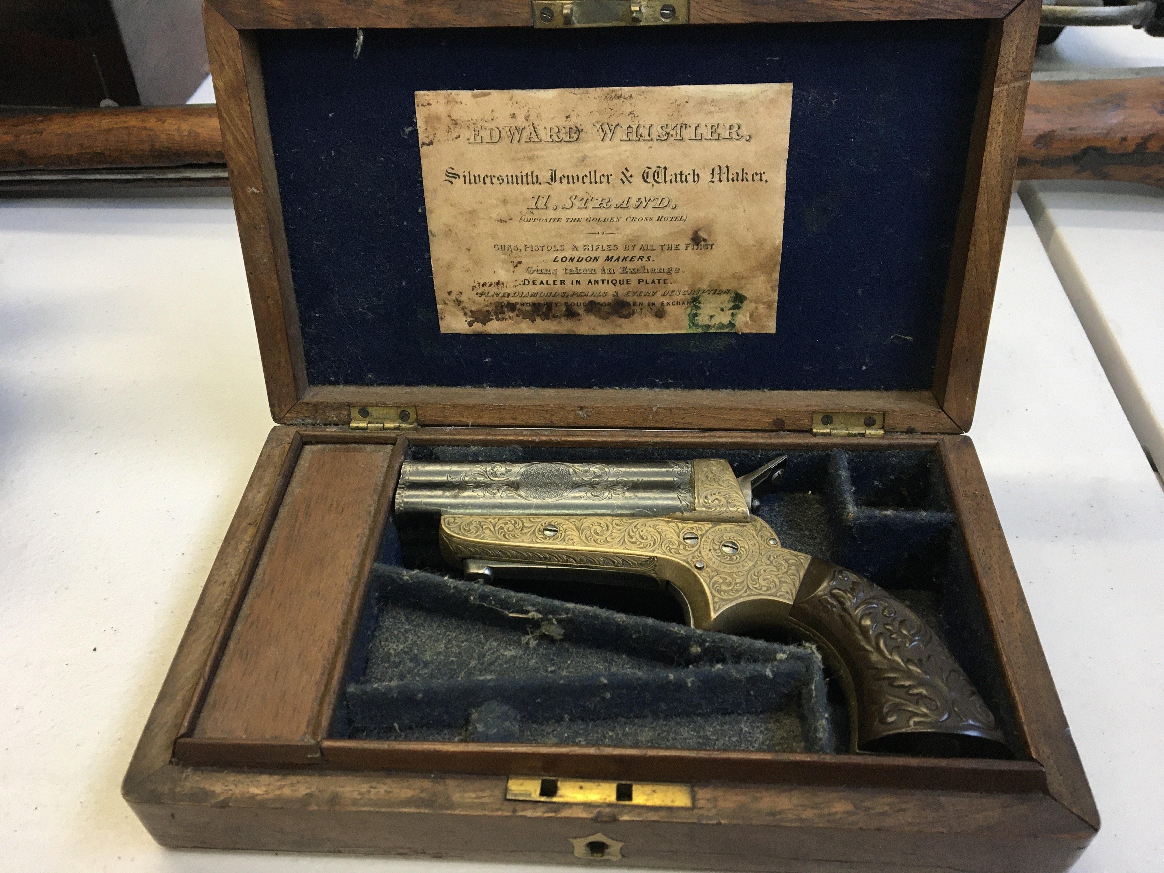 Tipping & Lawden of Birmingham A 19th Century .31 RF Sharp's Patent Four Barrel Repeating Pocket Pistol by Tipping & Lawden. The 3 steel barrels sliding forward for loading, engraved with foliate cartouche panels and with Birmingham proof marks, serial number 600 the silver plate frame richly engraved with scrolling acanthus leaves and flowerheads, with a signed circular panel, sheath trigger, barrel release catch to the underside, the two-piece composition grip scales moulded with acanthus leaves. 6 overall. GWO. Contained in fitted blue felt lined walnut case with brass escutcheon.