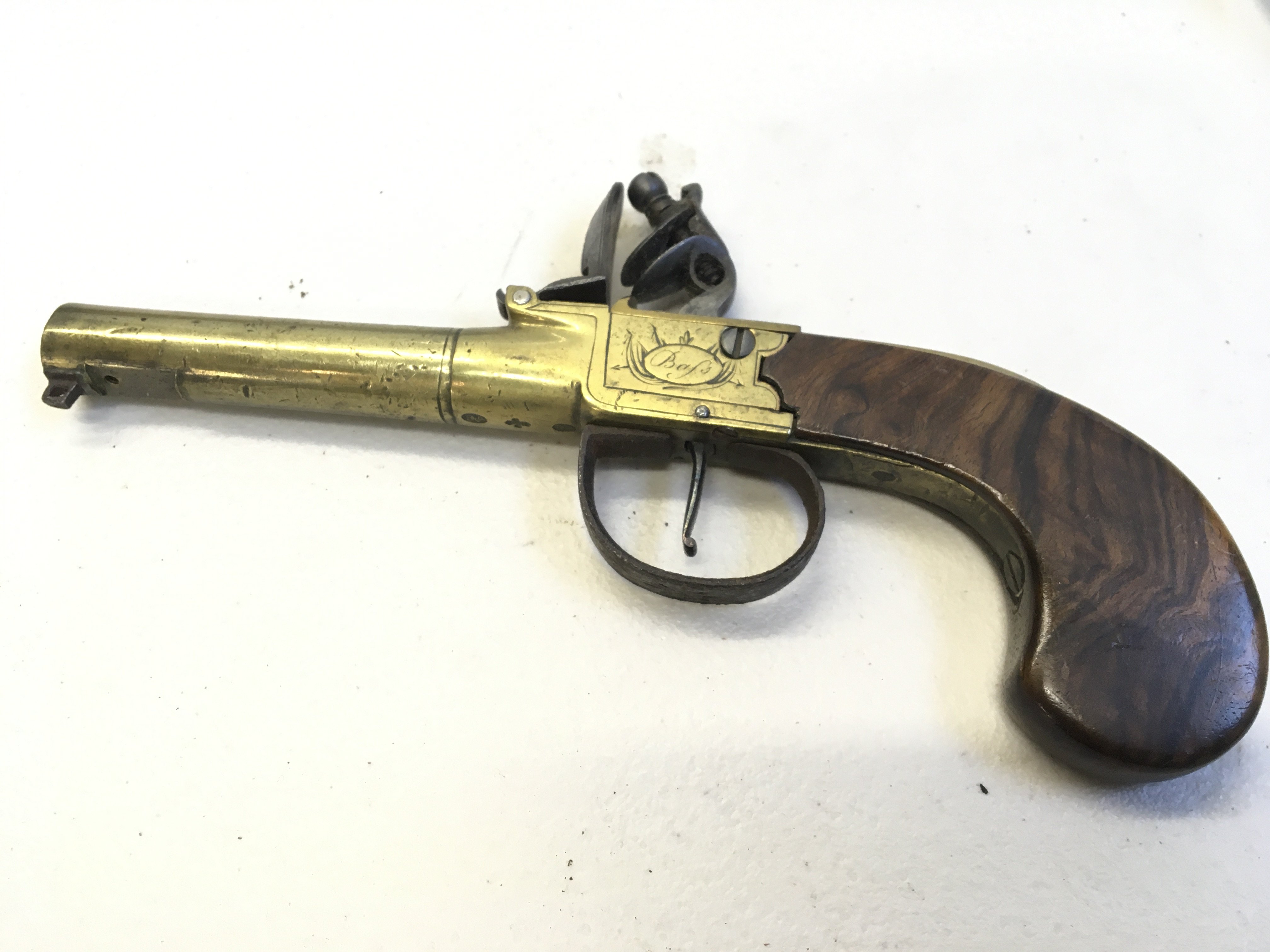 An Antique flint lock pistol with brass barrel and action walnut grip missing flick bayonet fitting. The action stamped Bafs London.