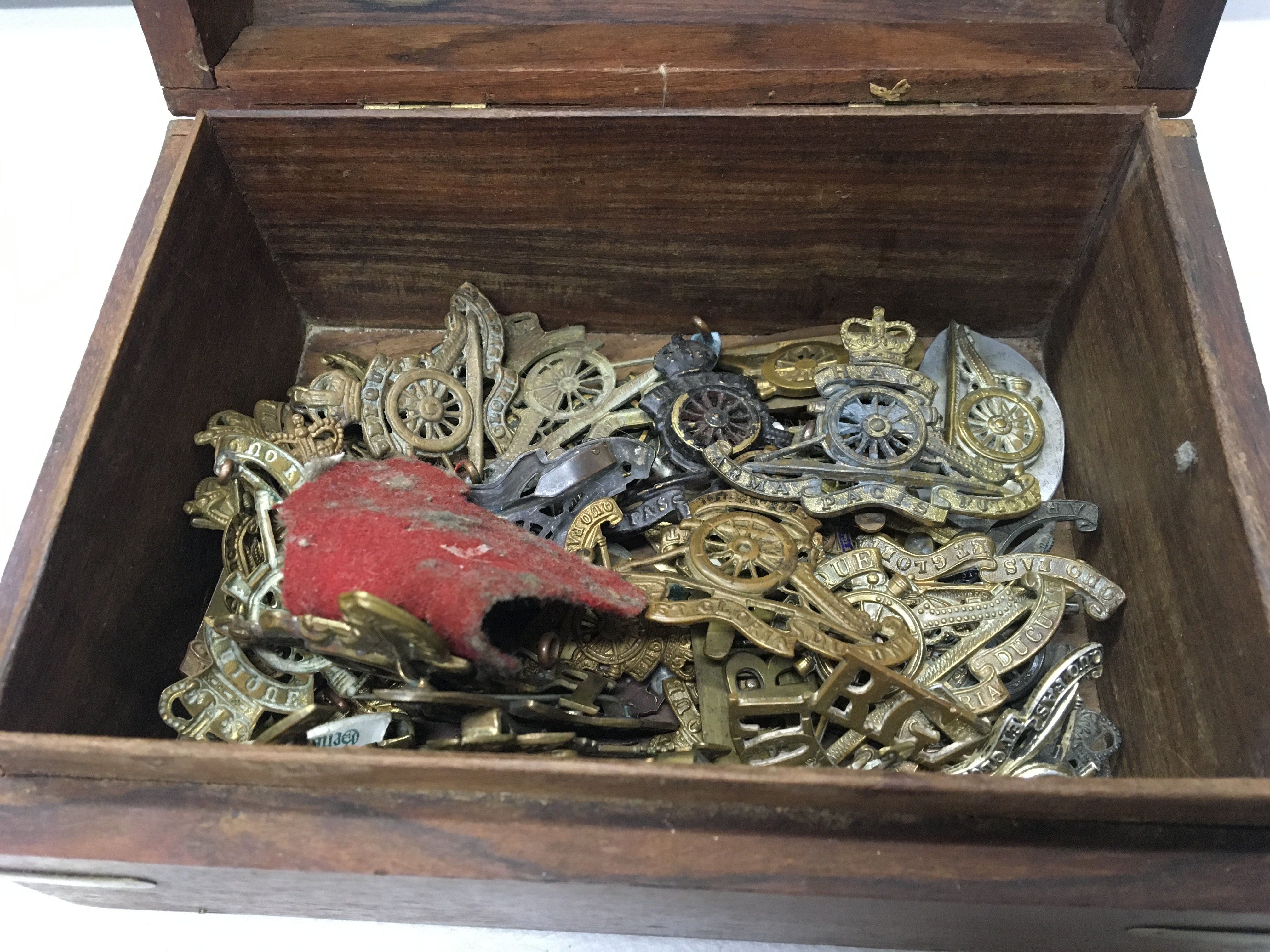 A box containing a quantity of British Royal Artillery badges and others.