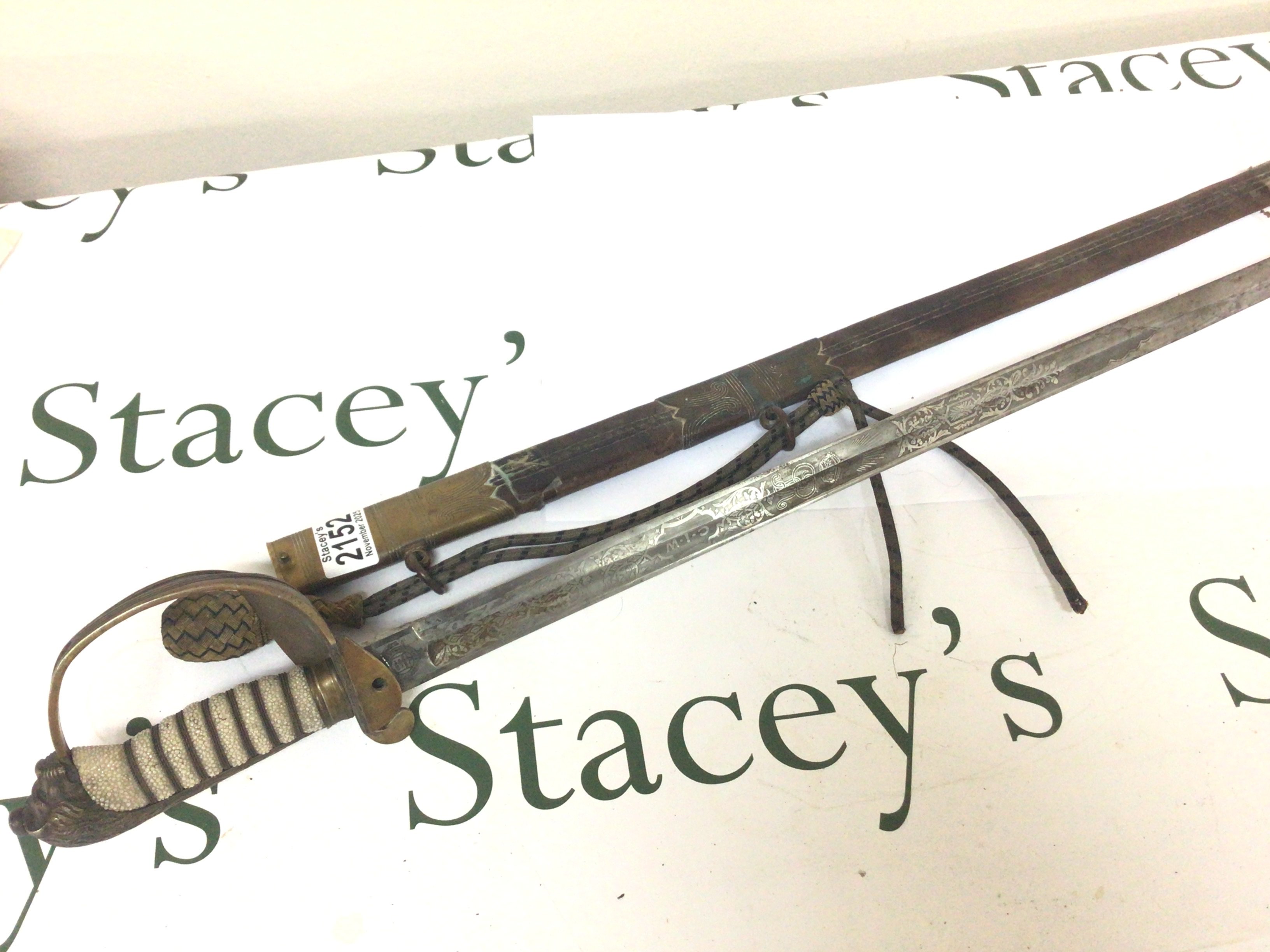 A British Officer Navy Sword RNR the sword the maker Fenton Bro Sheffield with wired shagreen grip brass fittings the blade with engraving including Royal cypher for George V. Leather and brass scabbard.