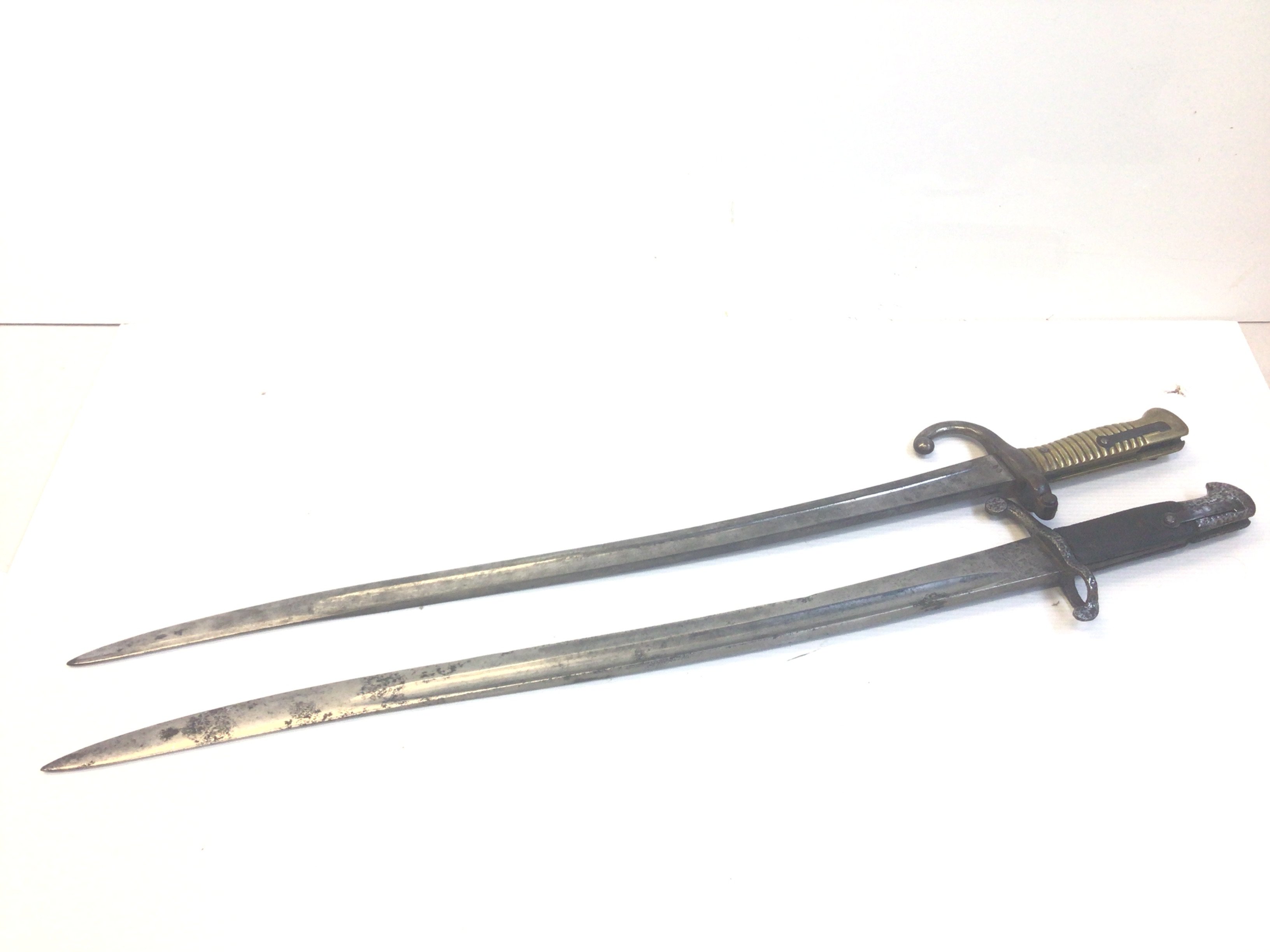 A French 1874 pattern bayonet with brass grip and one other bayonet without scabbed with unusual mark to the steel blade. (2)