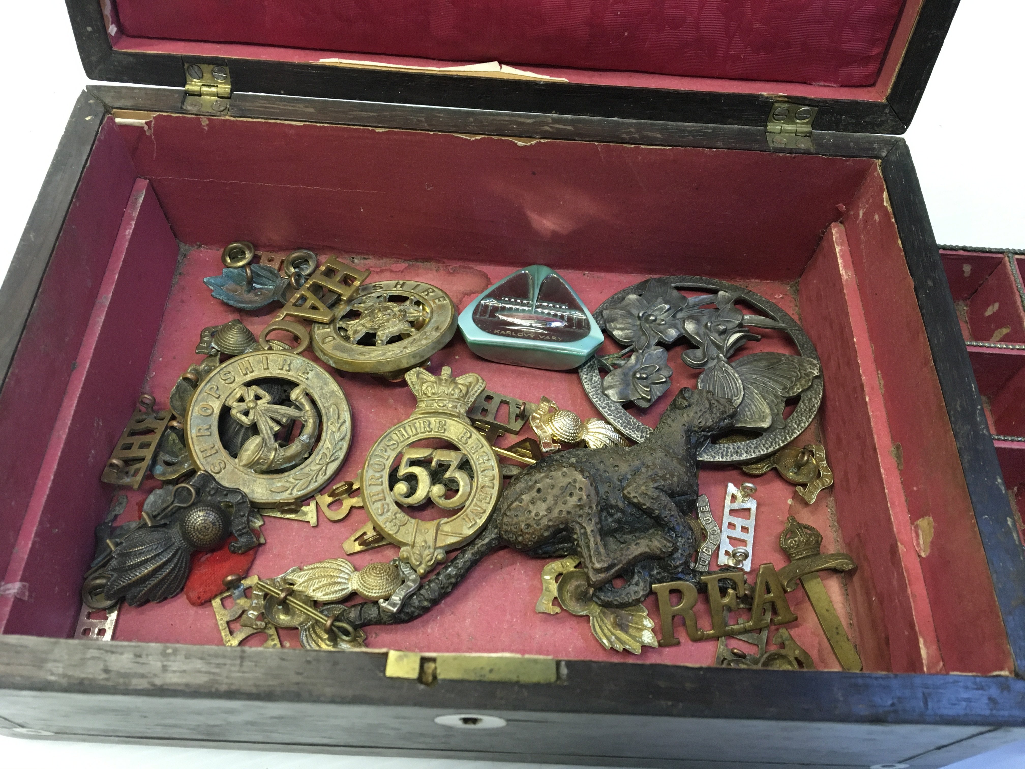 A Rosewood work box containing military badges. Including Shropshire and Derbyshire helmet badges.