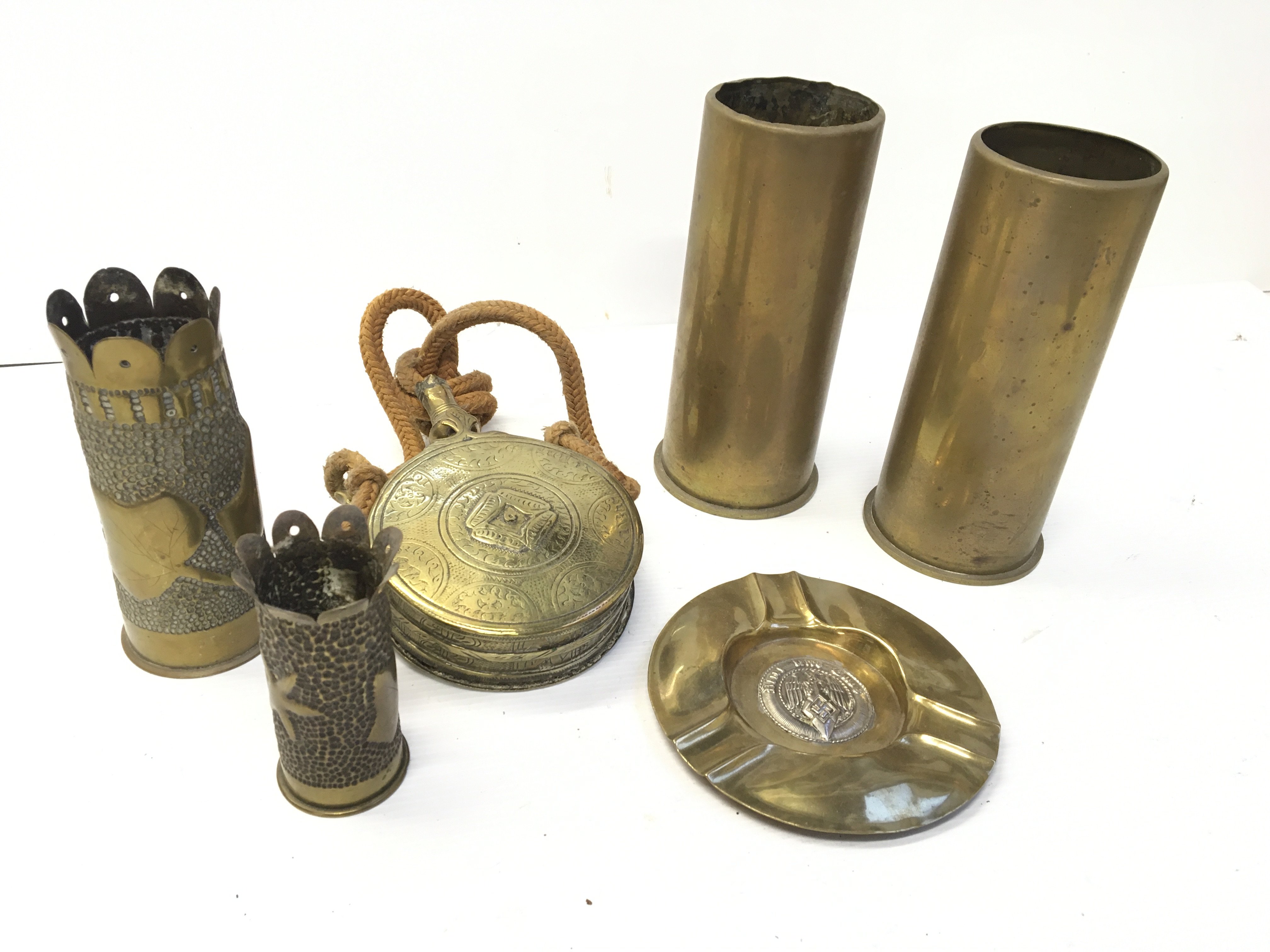 A German Third Reich brass and silver plated ash tray brass trench art shell cases a brass powder flask and other shell cases.