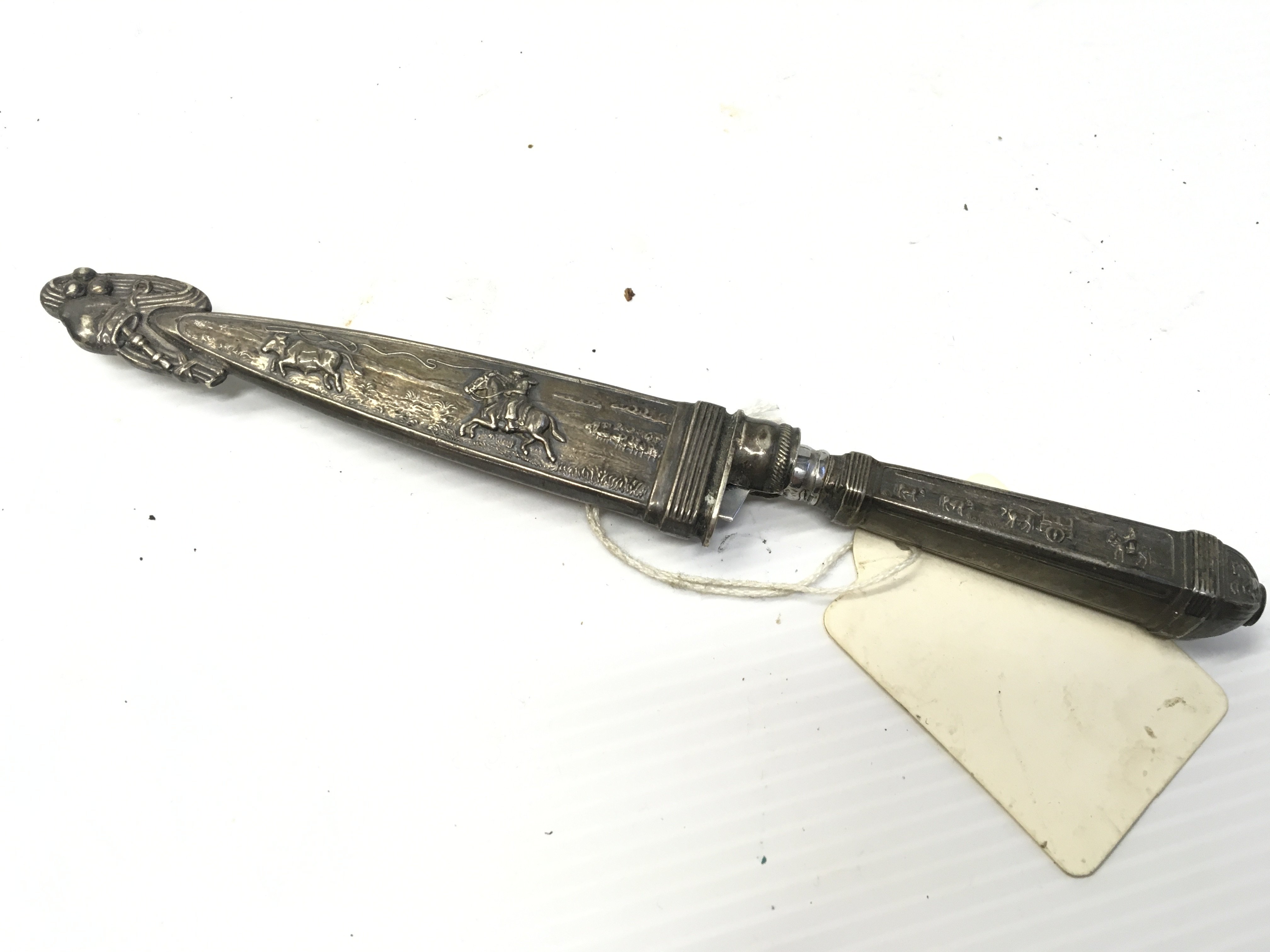 A Small white metal Gaucho knife decorated with cow boy theme stamped Inox