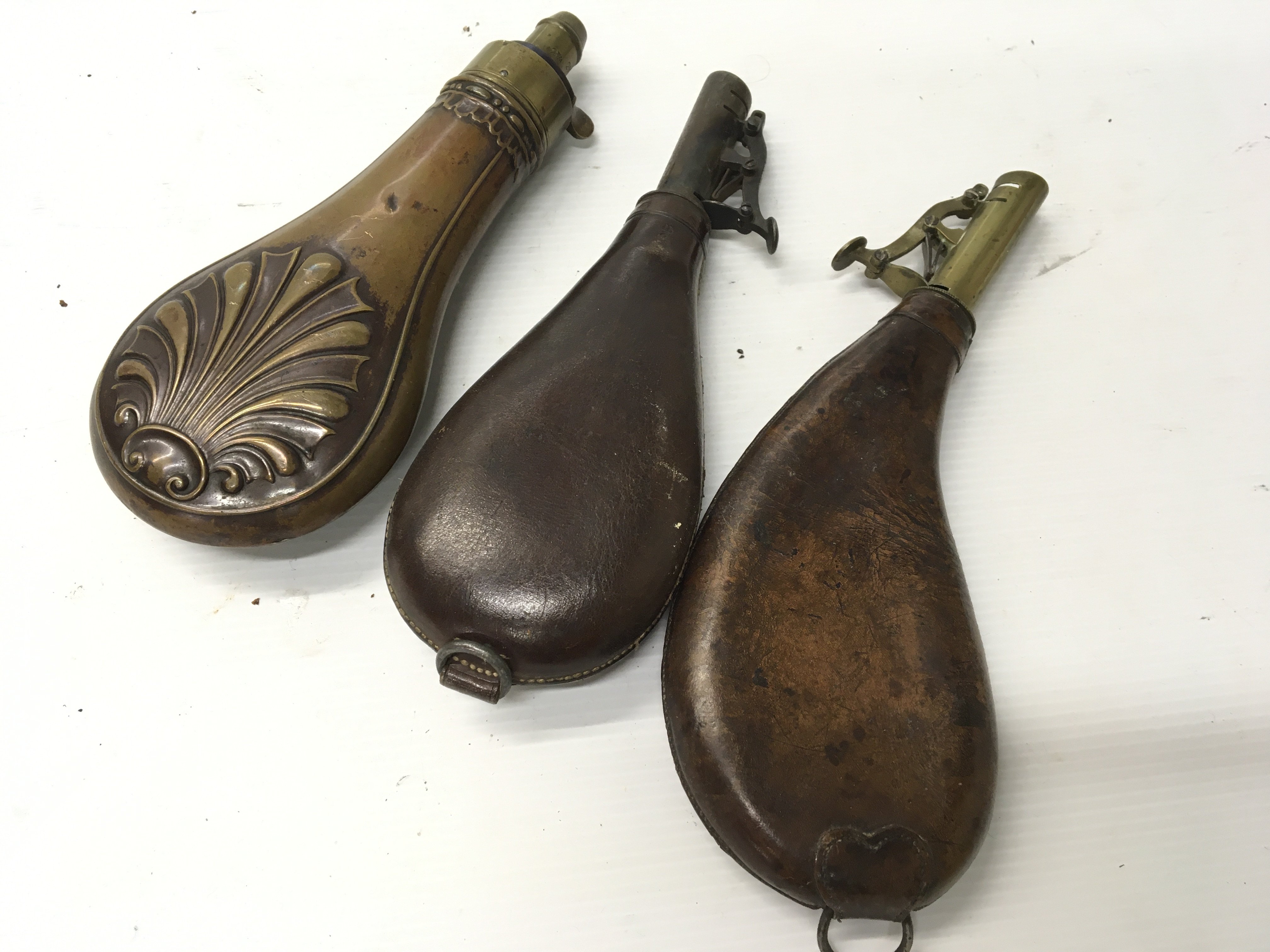 Two Antique leather and brass shot flasks and a copper powder flask (3)