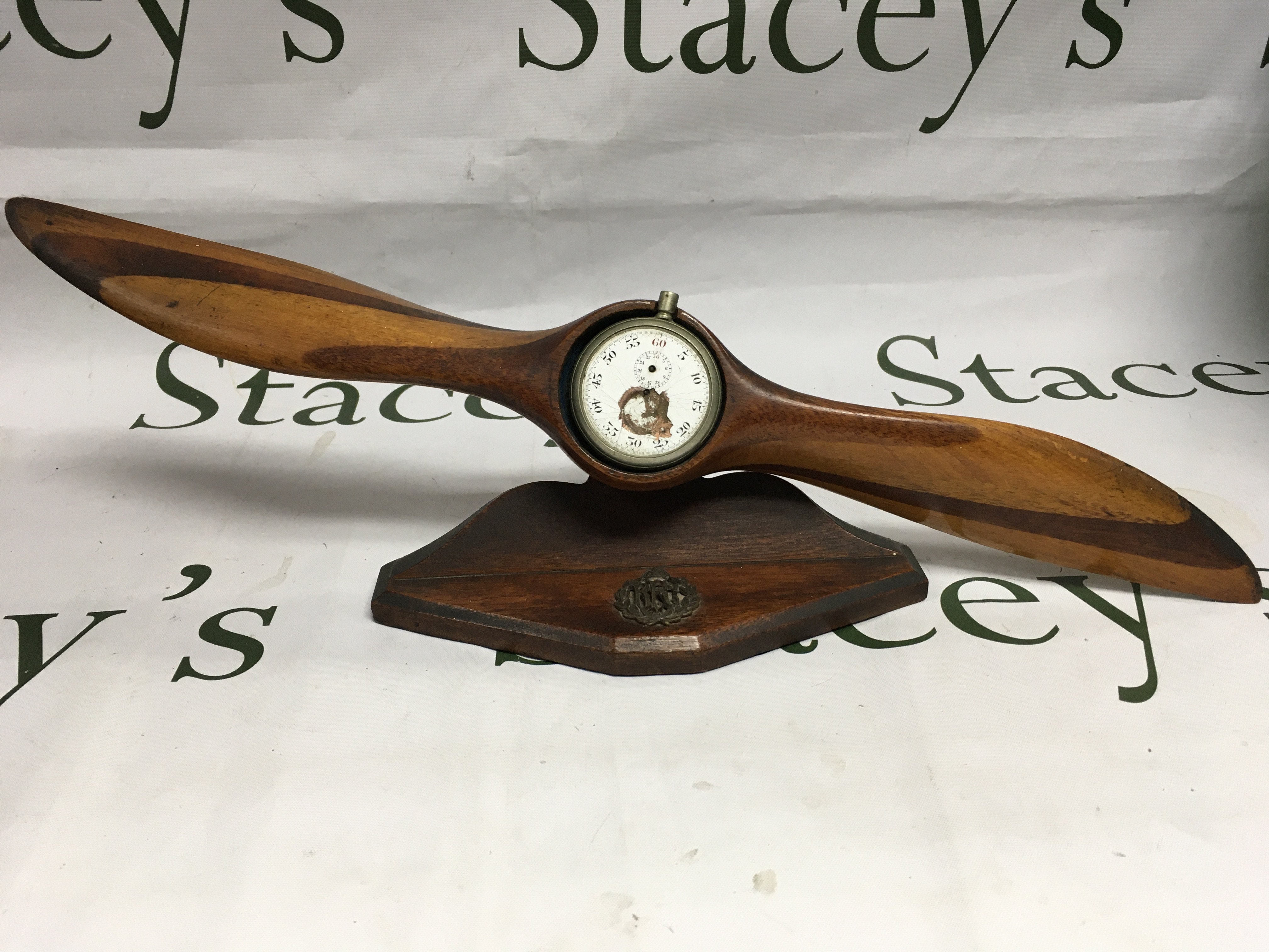 A WWI era auxiliary propeller (possible German) on a fitted stand and damaged pocket watch with RFC badge applied to stand.