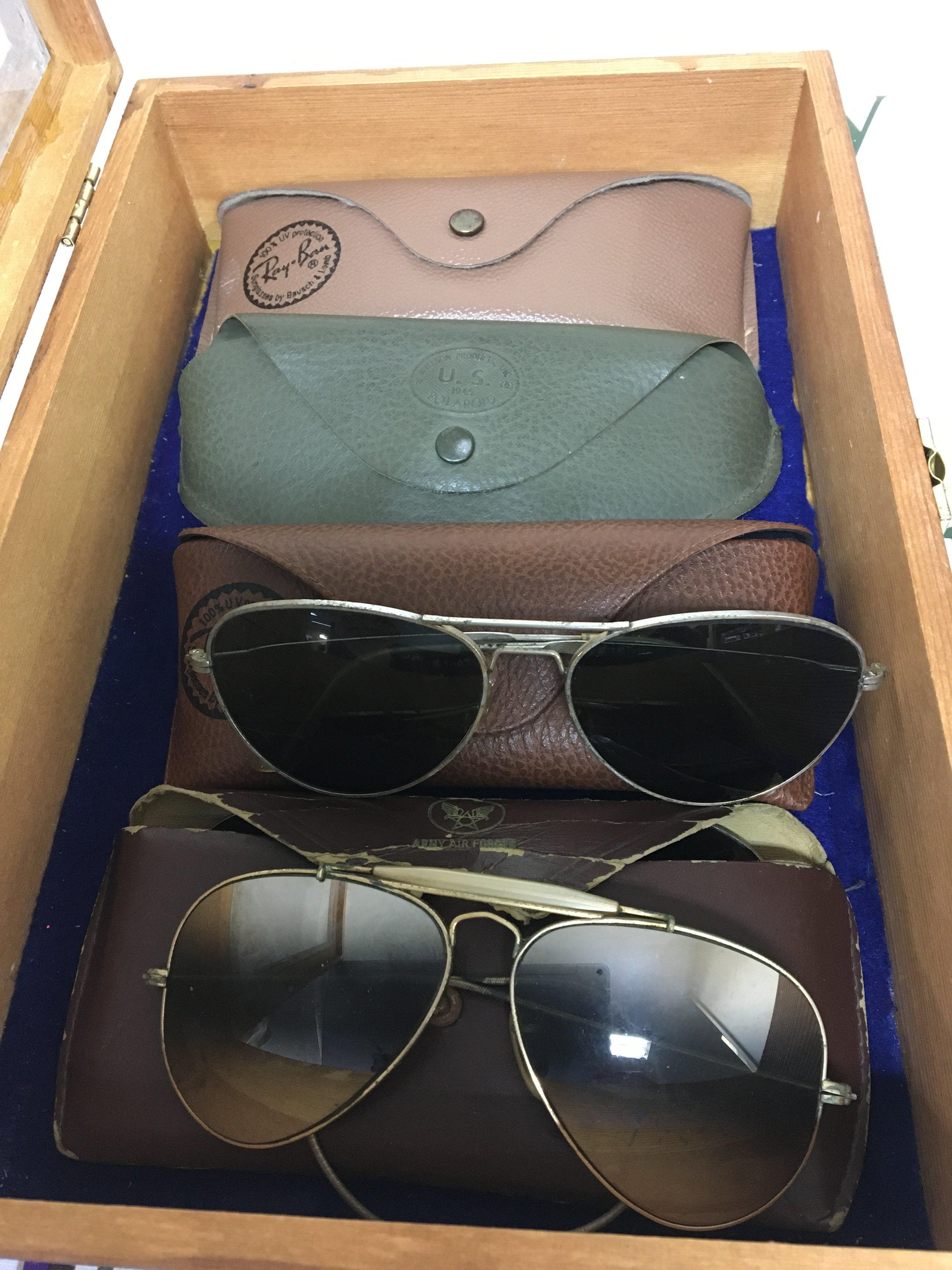 A collection of four pairs American 1940s and later Ray Ban sun glasses most likely worn by II world war American Military personnel one case stamped 1945 US Polaroideach pair with case in a wood display box. (4)