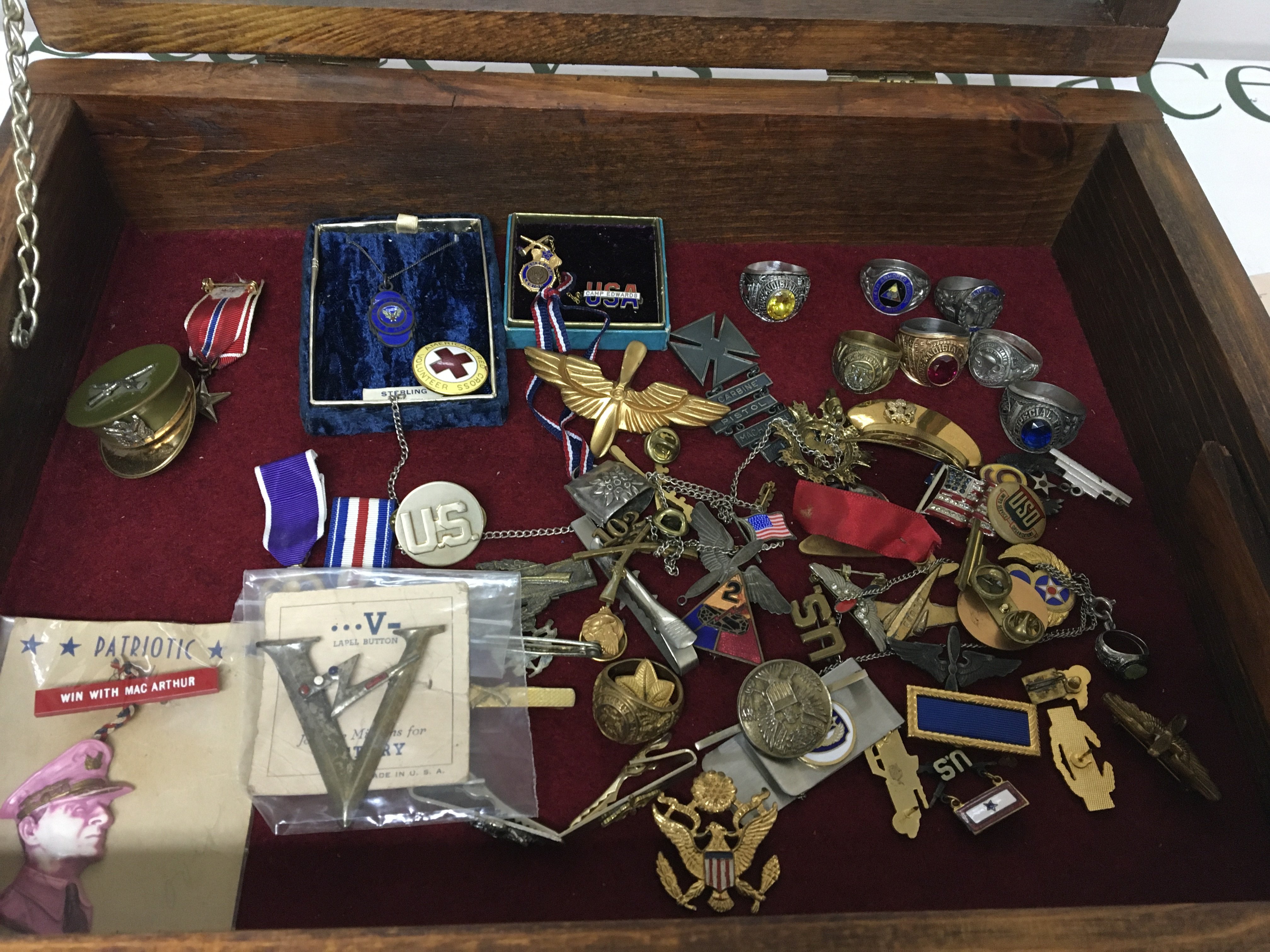 A case containing American military and other badges including an enamel ring 14th Armoured Division American Paratroopers other rings and associated badges.